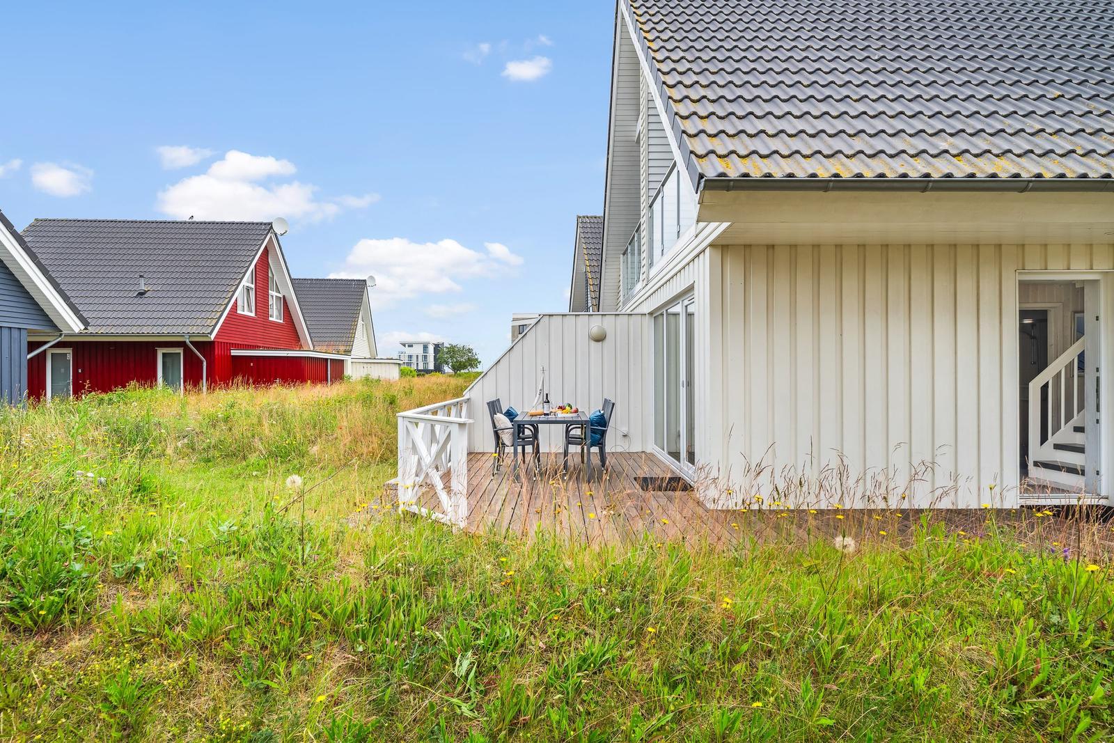 Wohnhaus mit Terrasse und Garten. Im Hintergrund rote Häuser.