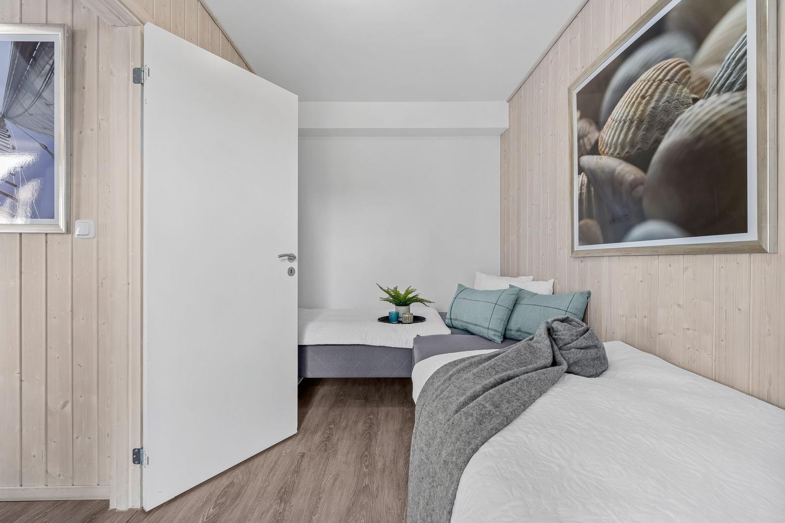 Schlafzimmer mit zwei Betten, Holzwänden und Wandbildern.