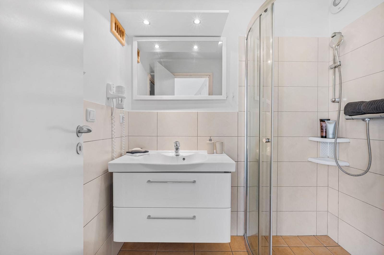 Badezimmer mit Dusche, Waschbecken und Spiegel