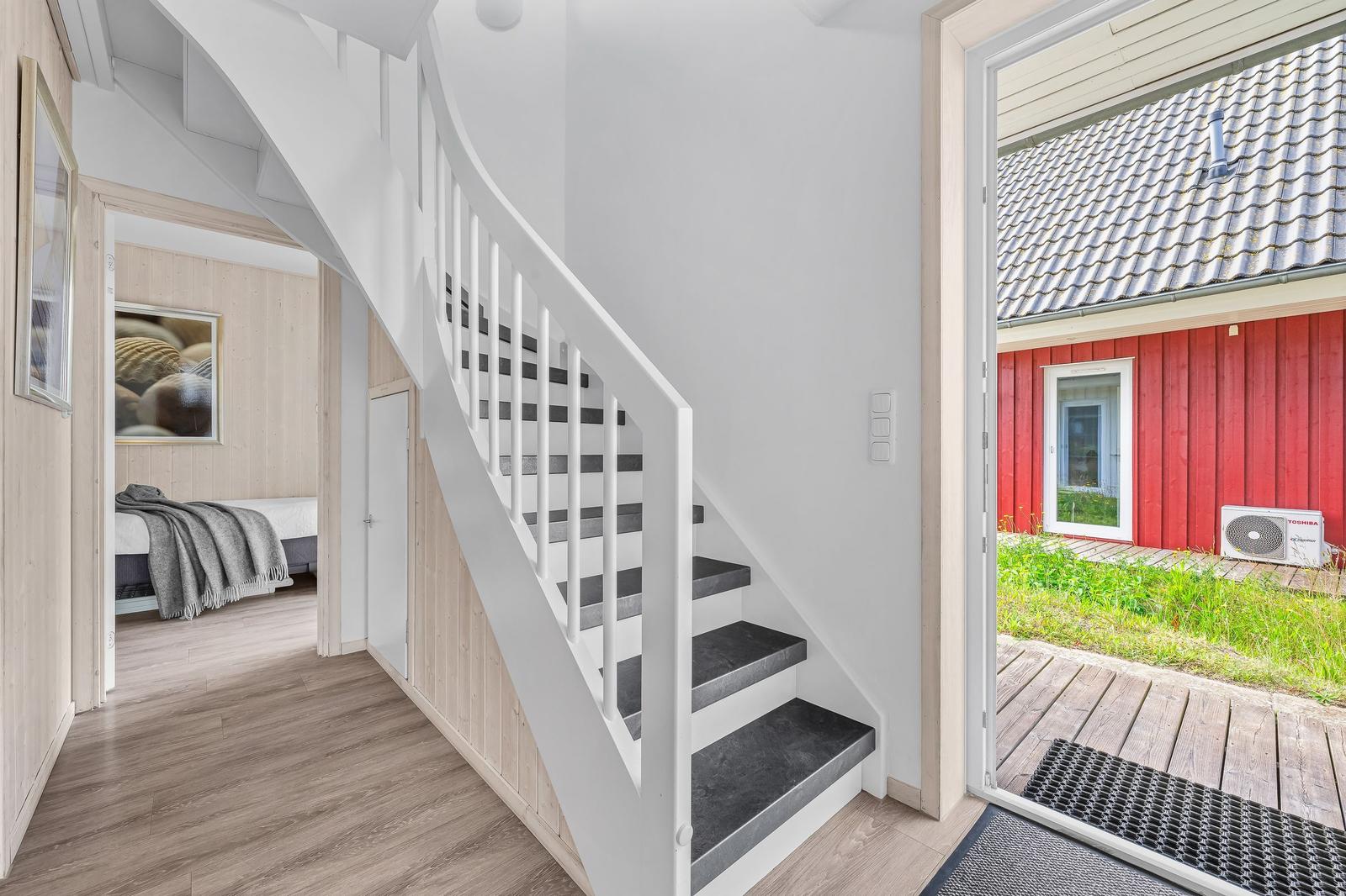 Treppenhaus mit Blick auf einen roten Anbau und Schlafzimmer mit Bett und Wandbild.