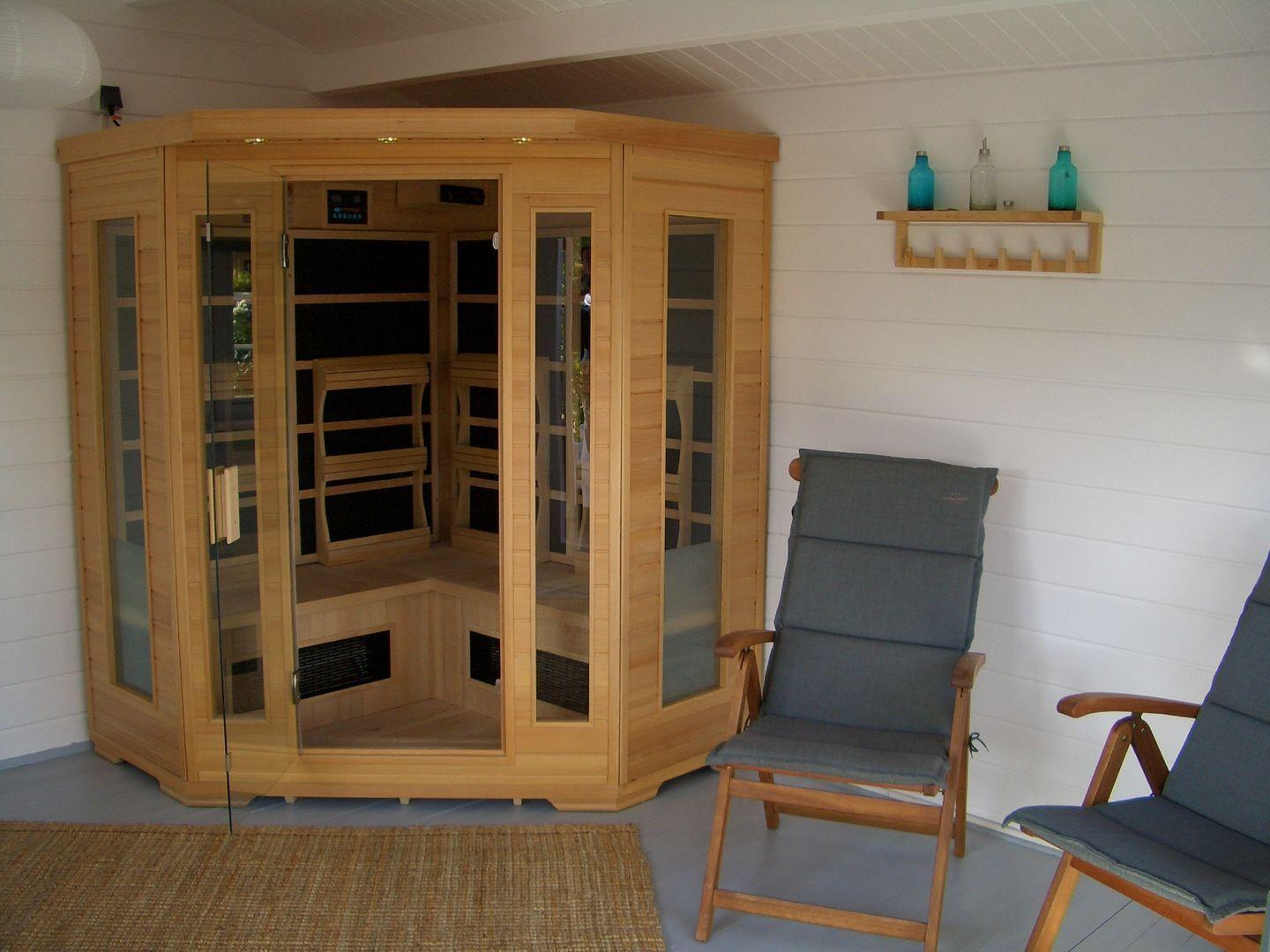 Holzsauna mit Sitzbänken und zwei Stühlen daneben.