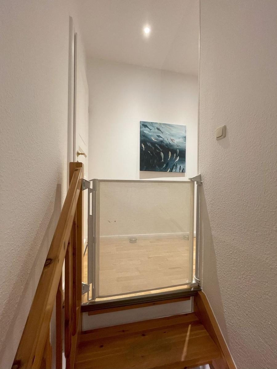 Holztreppenhaus mit Kindersicherung und Wandbild.