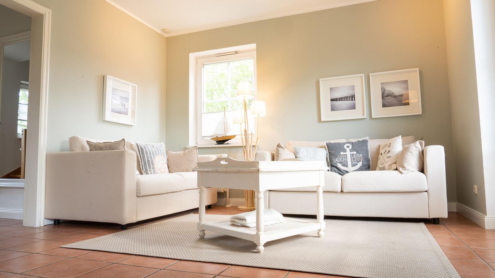 Wohnzimmer mit zwei Sofas, Tisch und Fenster. Wandbilder und Stegmodell.