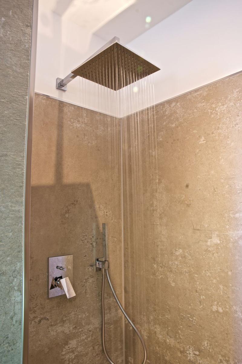 Dusche mit bodentiefem Regenduschkopf und Handbrause an Steinwand