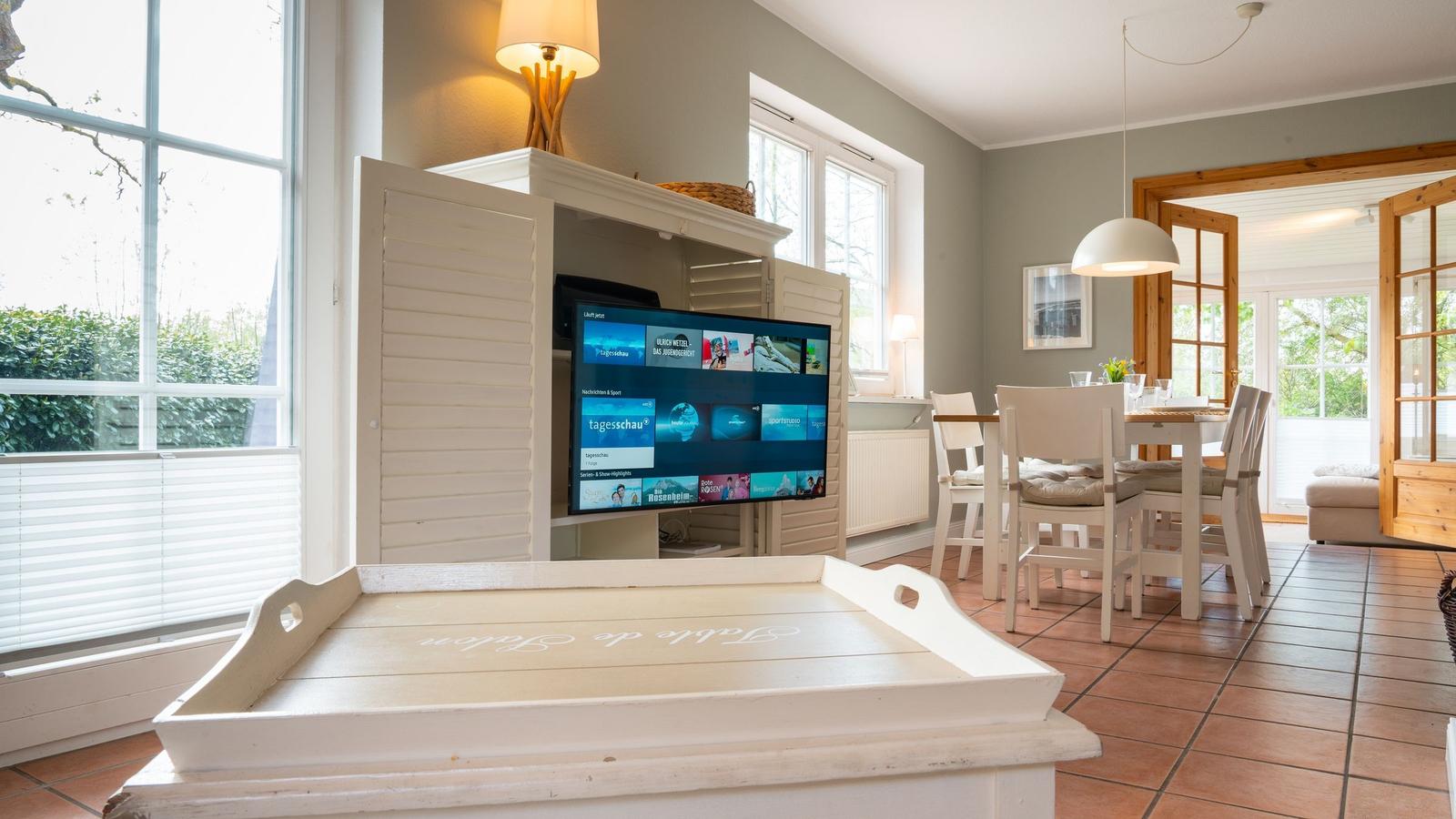 Wohnzimmer mit Fernseher, Essbereich und Fenster zur Außenseite.