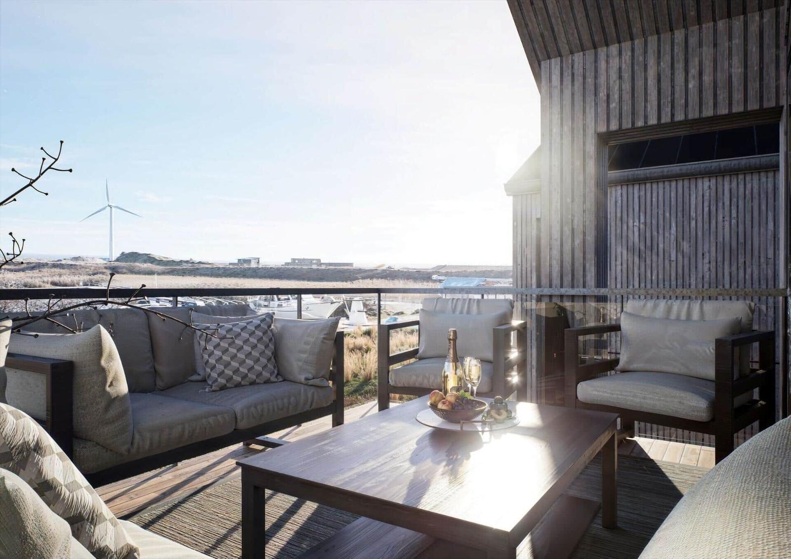 Terrasse mit Sitzgruppe und Tisch. Blick auf Windkraftanlage und Landschaft.