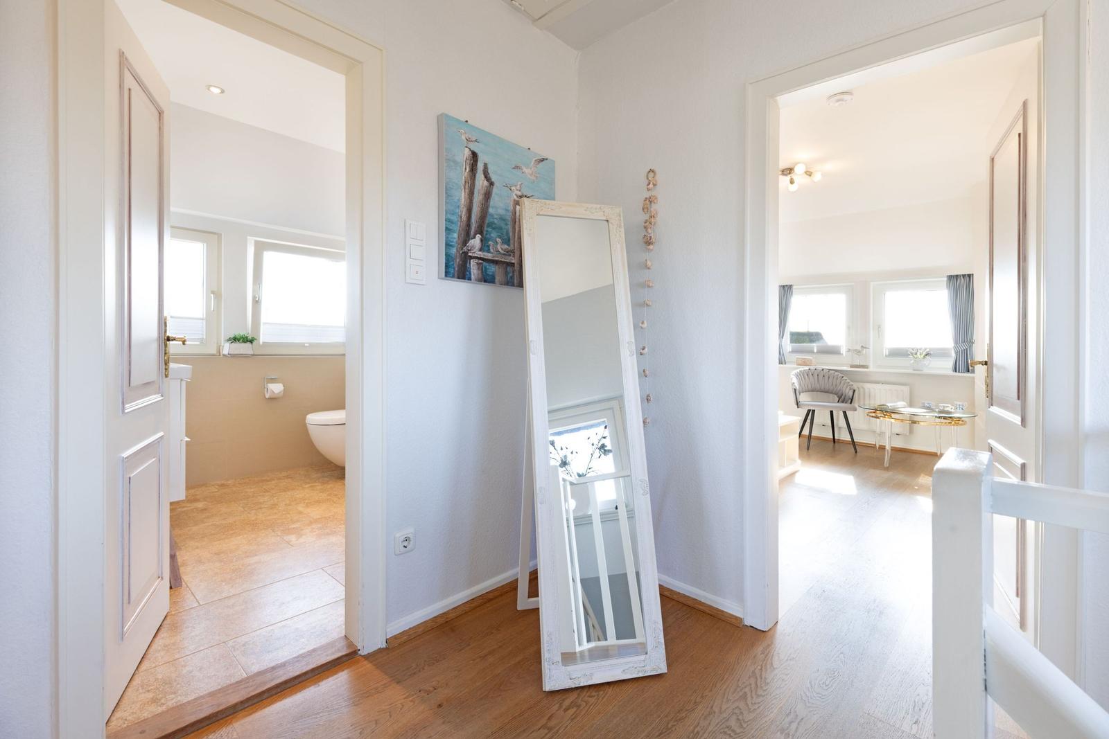 Hallenflur mit Spiegel, Badezimmer und Schlafzimmer sichtbar.