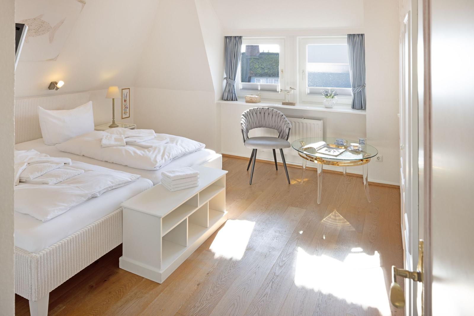 Schlafzimmer mit Doppelbett, Sitzgelegenheit und Fenster mit Blick.