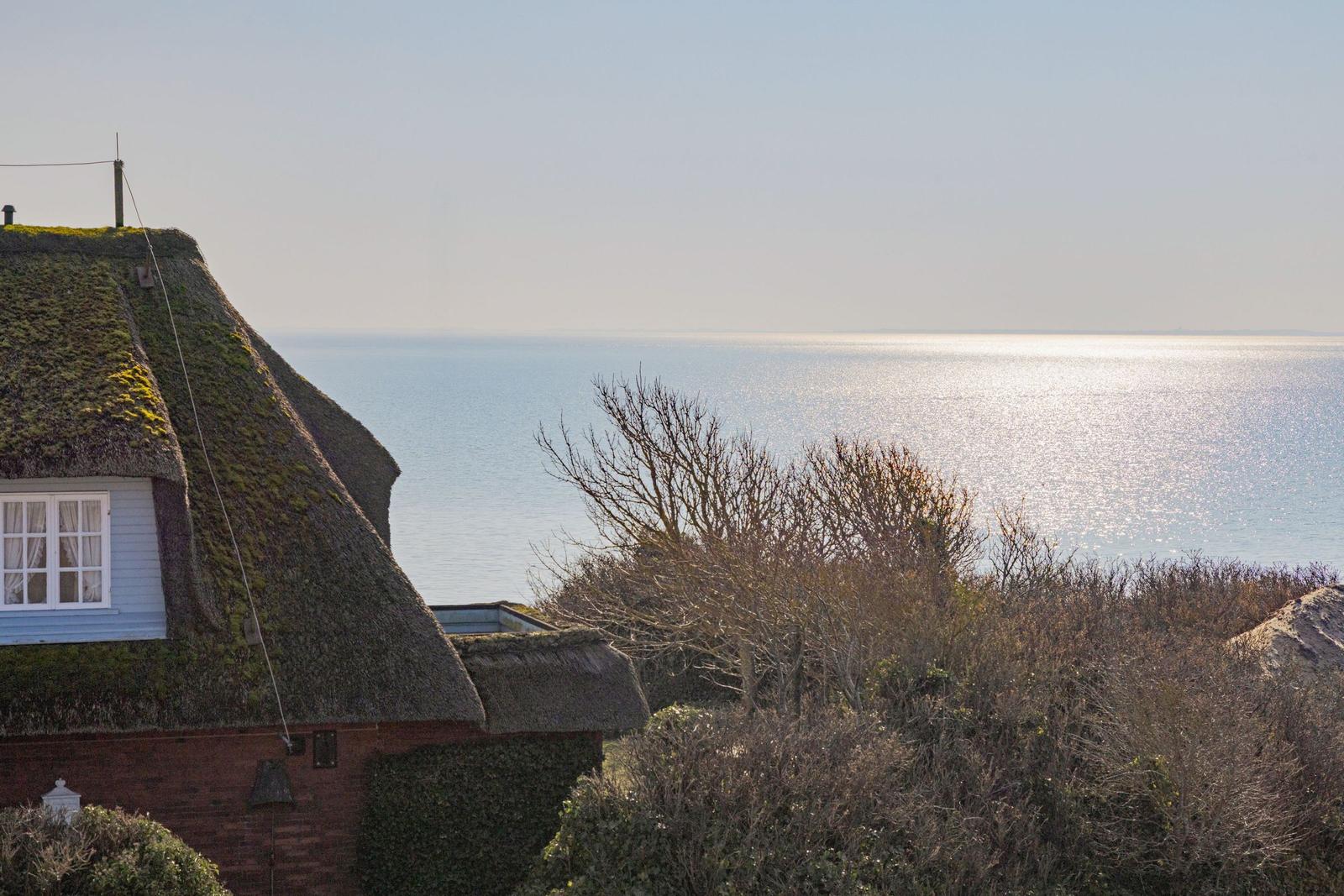 Haus mit strohgedecktem Dach und Blick auf das Meer.