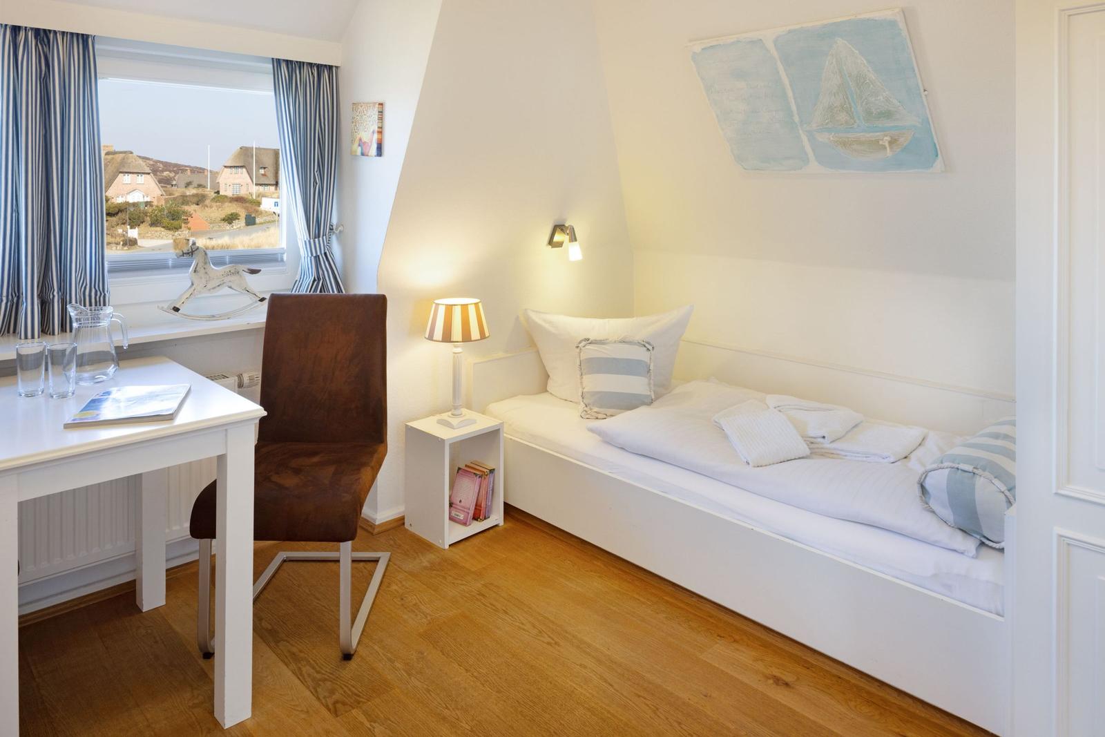 Zimmer mit Bett, Schreibtisch und Fensterblick auf Dörfer.