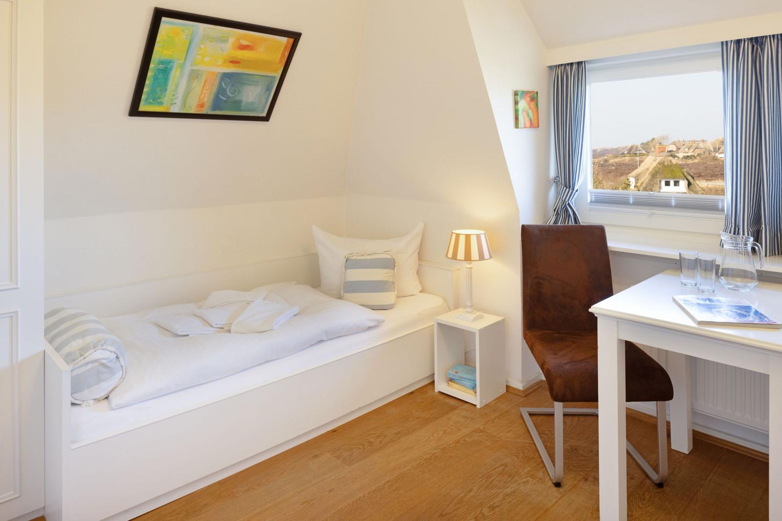 Schlafzimmer mit Bett, Schreibtisch und Fenster mit Blick.
