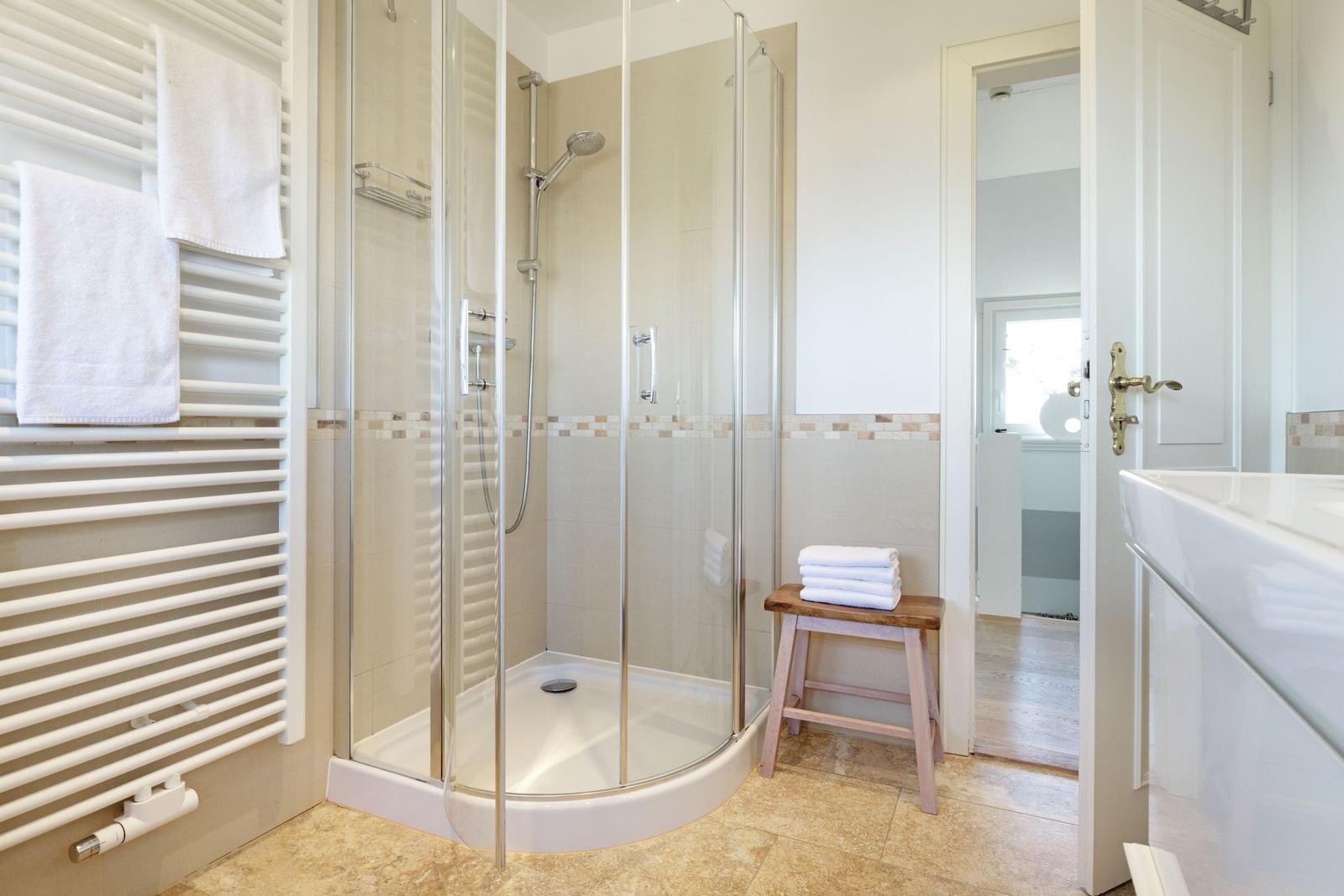 Dusche mit Glaswand, Handtuchhalter und Holzstuhl