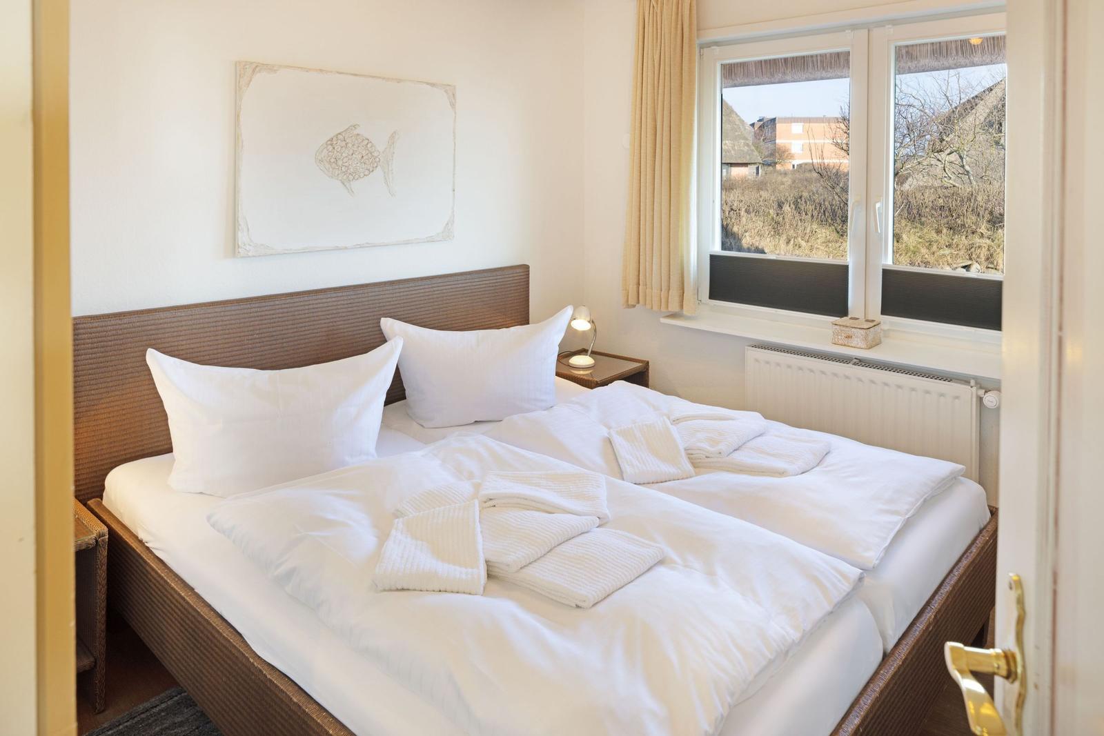 Schlafzimmer mit Doppelbett, Fenster und Wandbild.