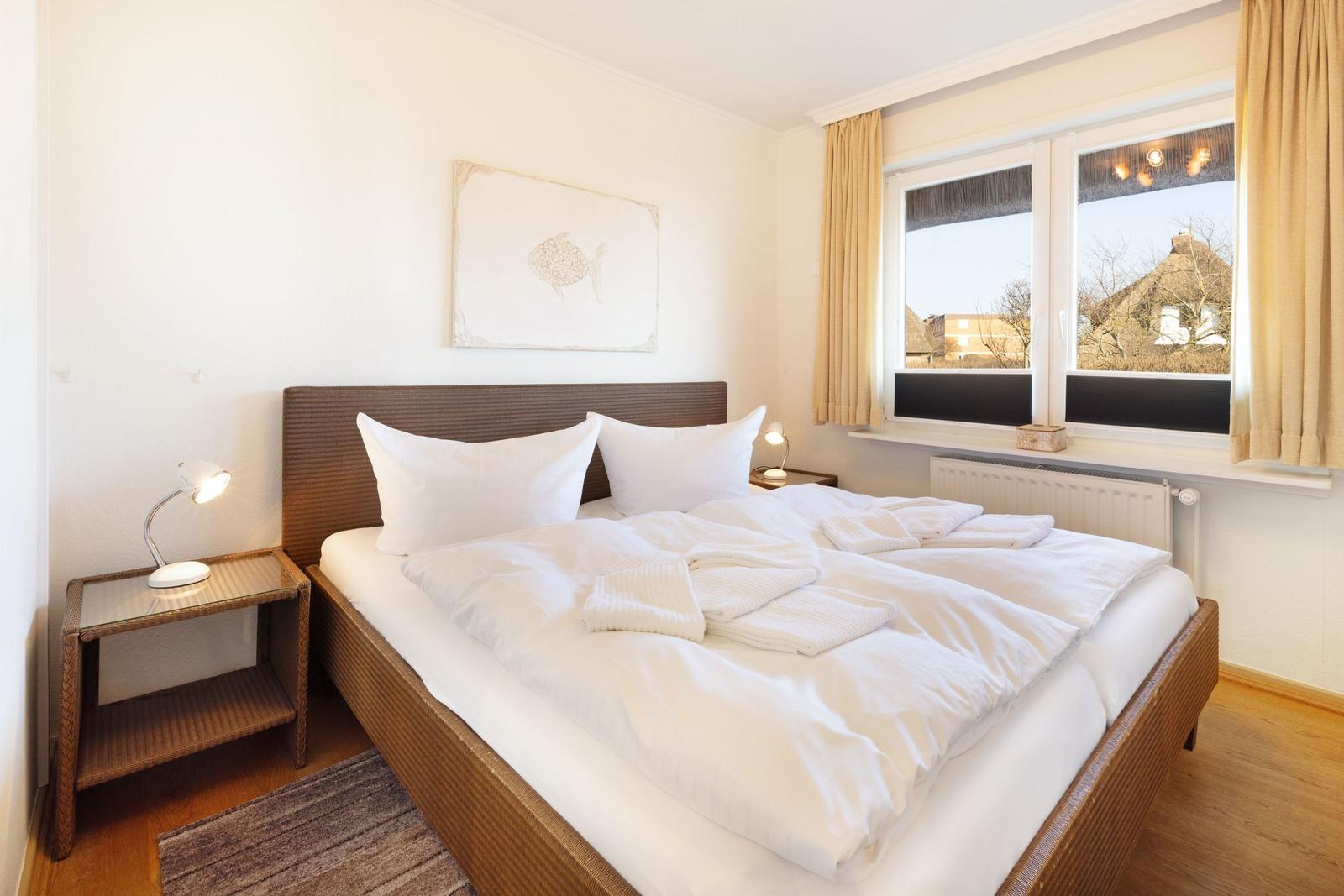 Schlafzimmer mit Doppelbett, Nachttisch und Fenster mit Blick.