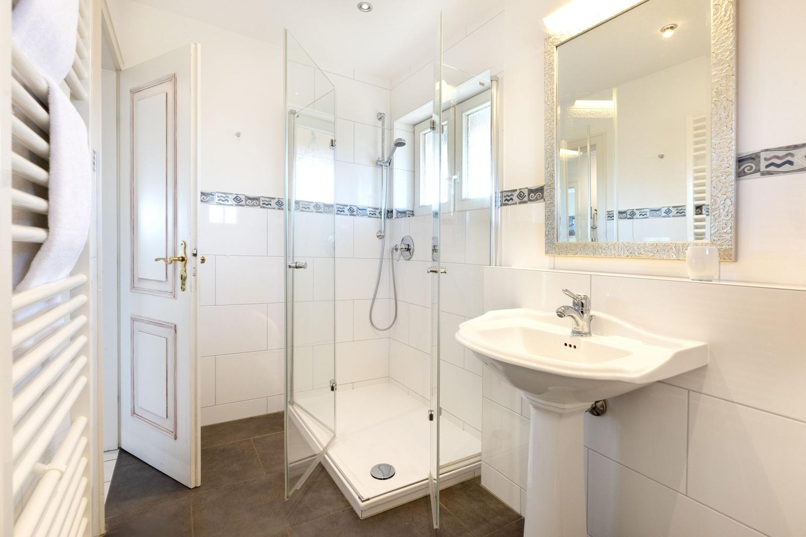 Badezimmer mit Dusche, Waschbecken und Spiegel