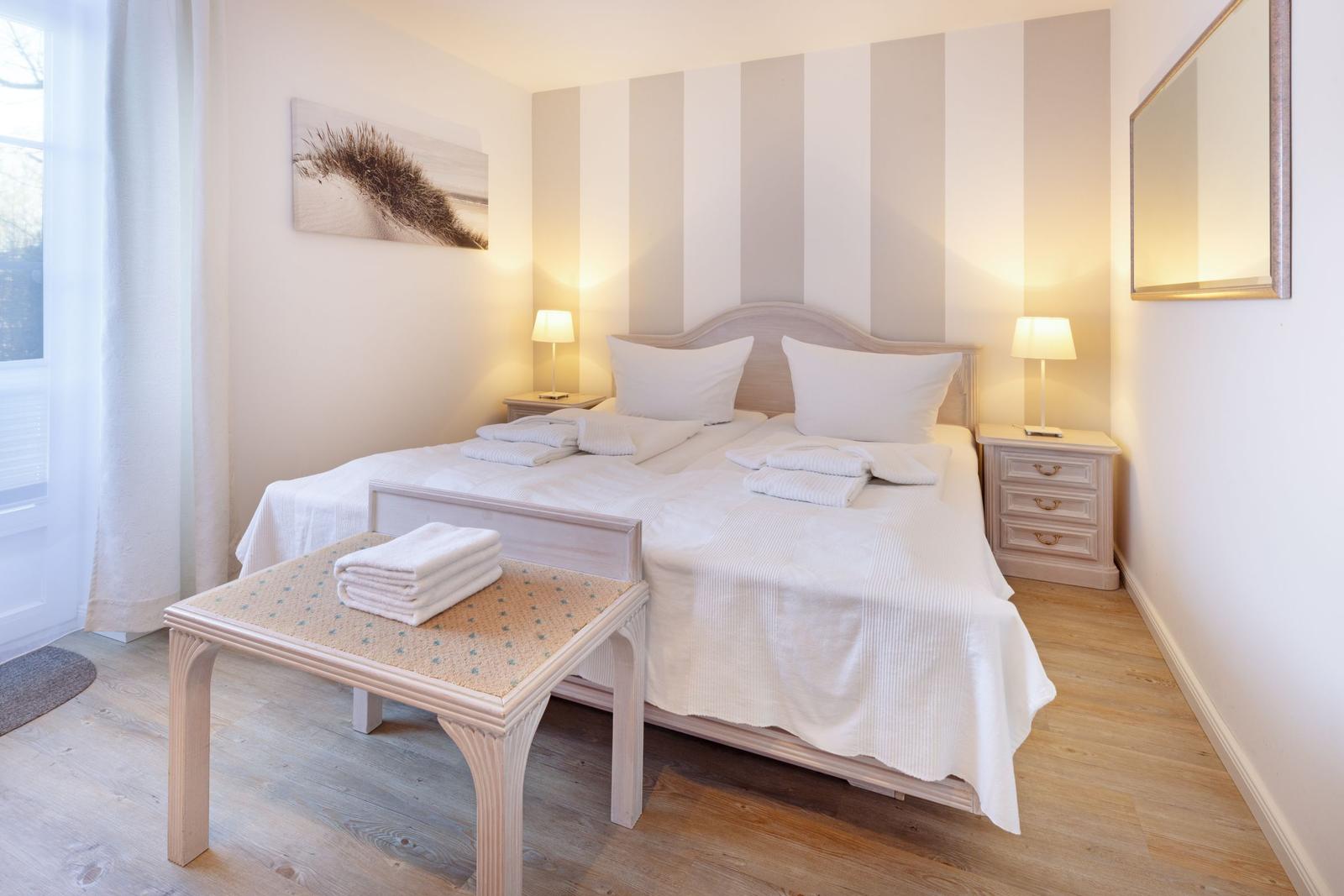 Ein Schlafzimmer mit Doppelbett, zwei Nachttischen und einem Fenster mit Vorhängen.