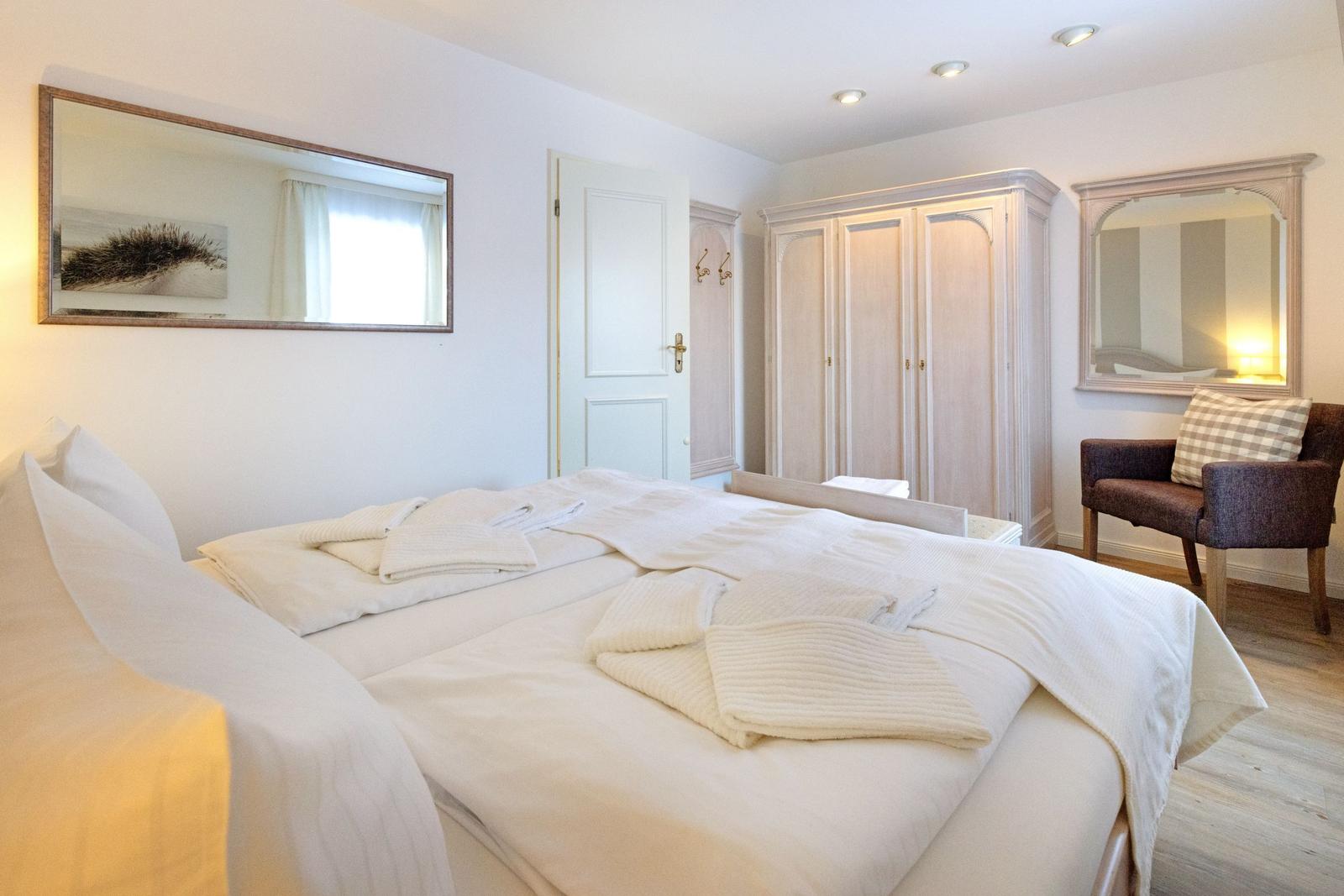 Schlafzimmer mit Bett, Kleiderschrank und Sessel.