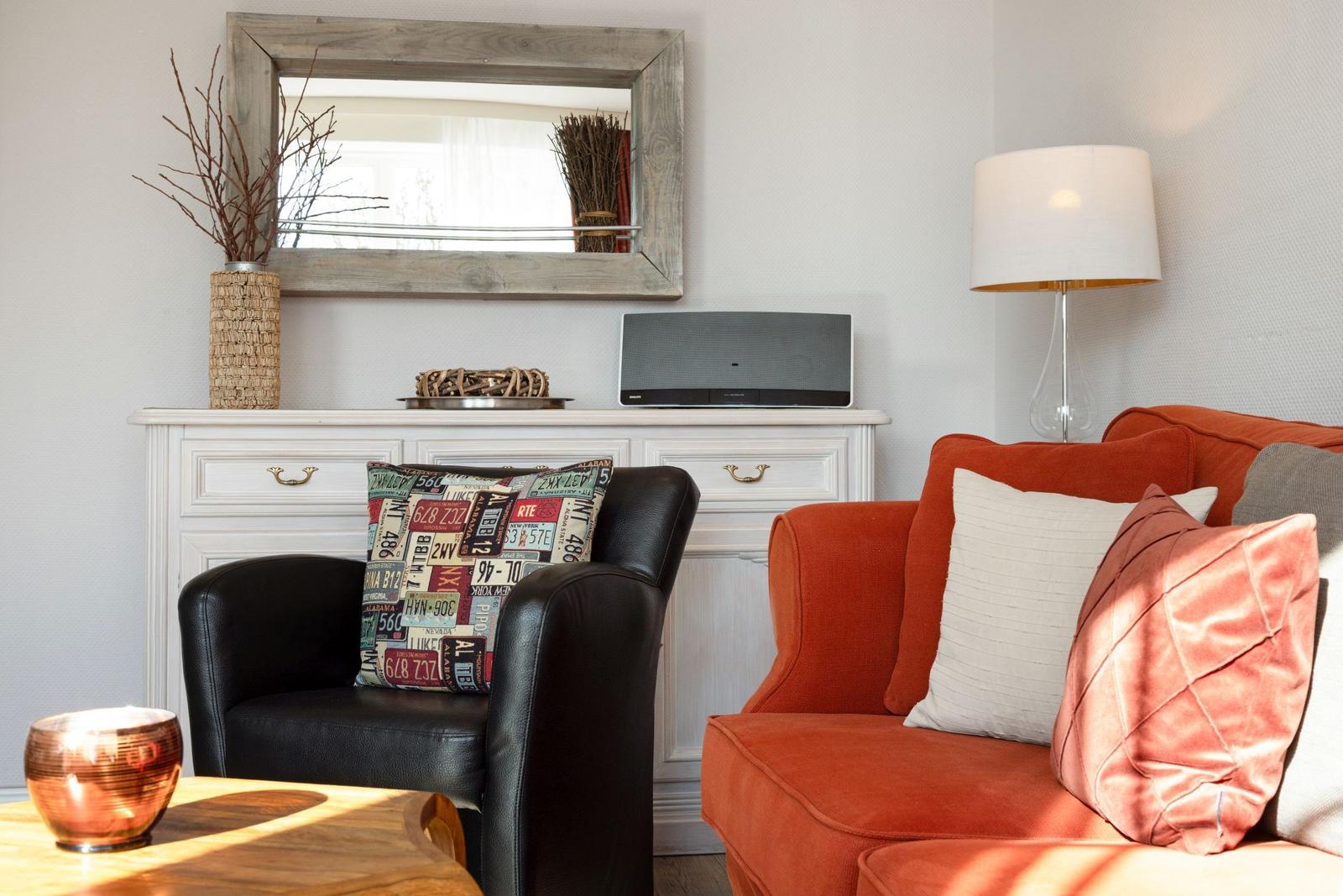 A living room with a red sofa, a black chair, and a white cabinet.