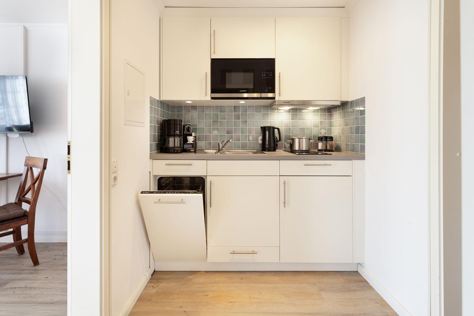Kitchen with white cabinets, microwave, sink, and integrated dishwasher.