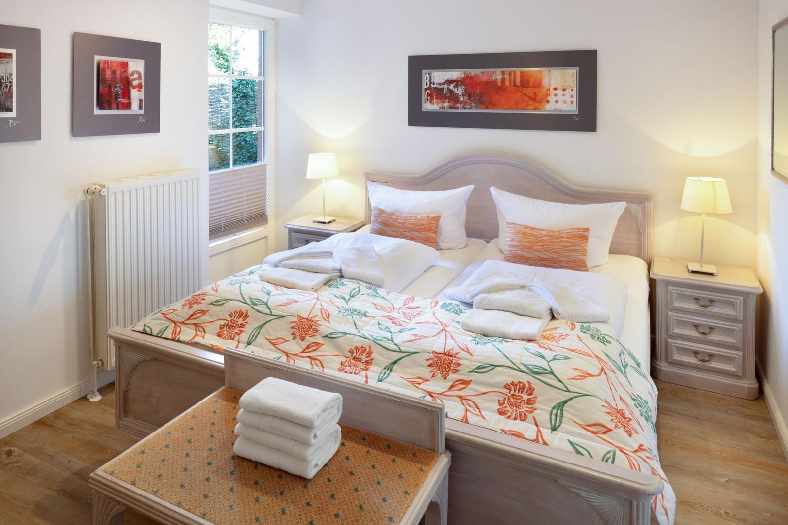 Bedroom with double bed, nightstands, and window. Towels are on the bed.