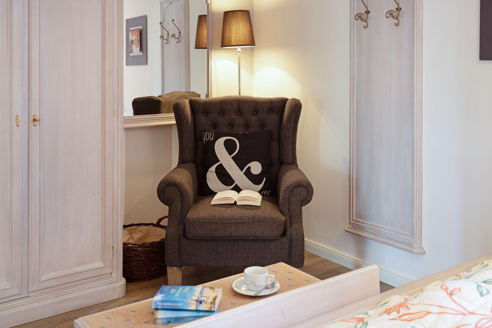 A brown armchair with cushion and book stands next to a wardrobe.