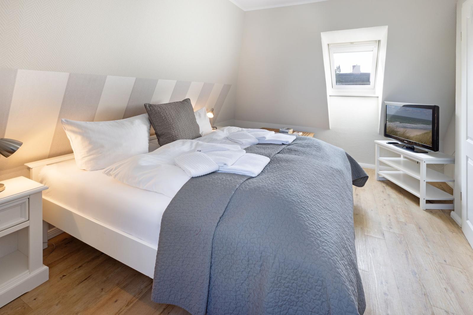 Schlafzimmer mit Bett, Fernseher und Fenster