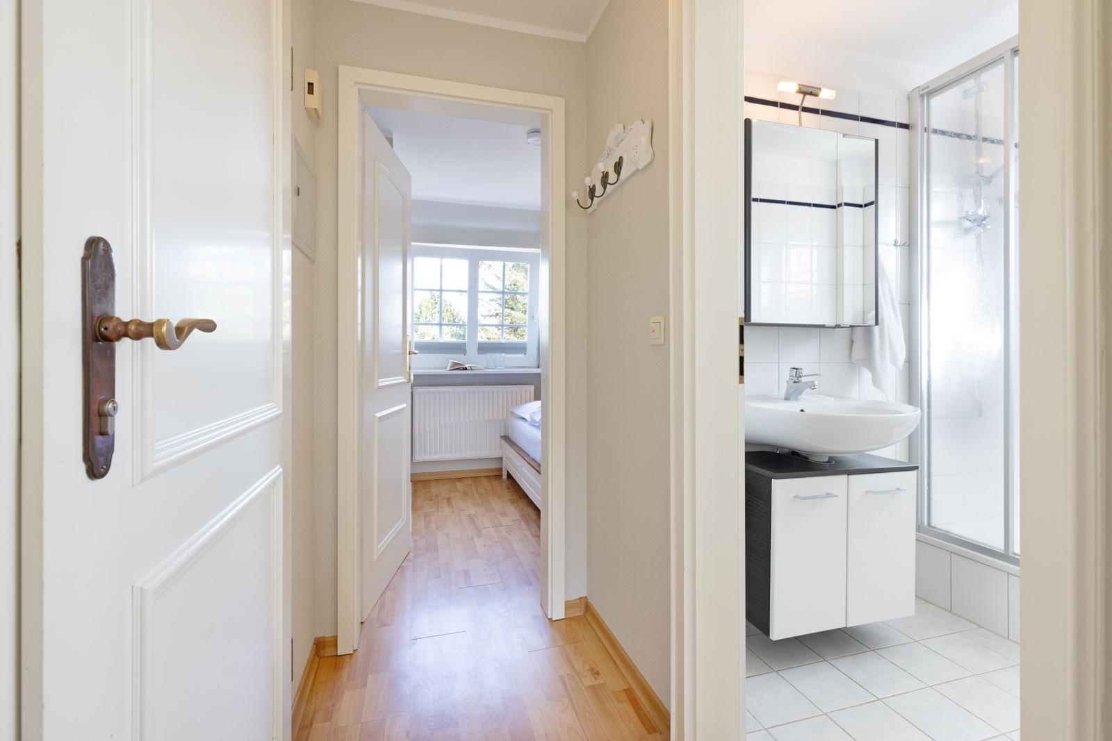 Flur mit Schlafzimmer und Badezimmer. Badezimmer mit Dusche und Waschbecken.