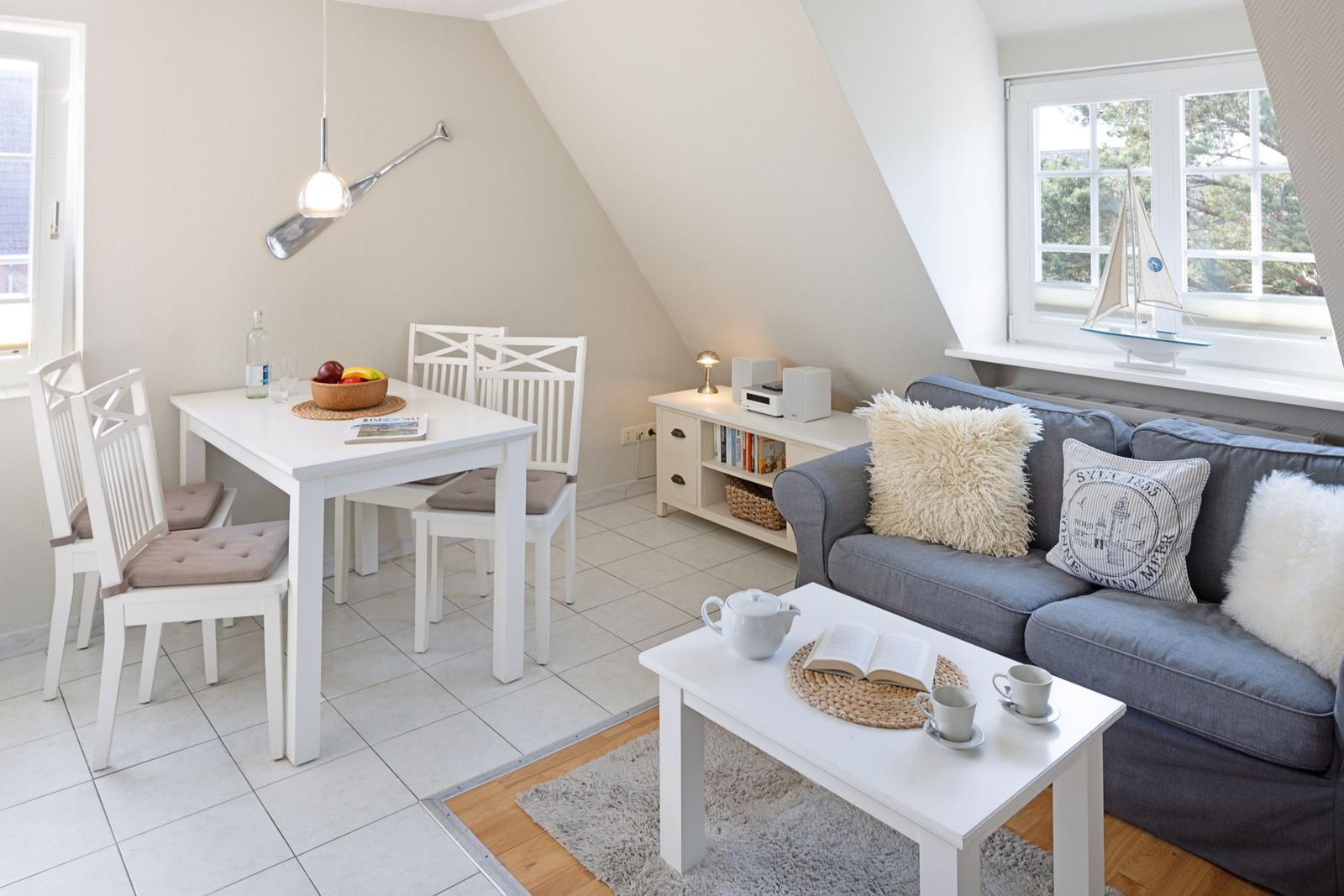 Wohn- und Essbereich mit Sofa, Tisch und Stühlen unter Dachschrägen.