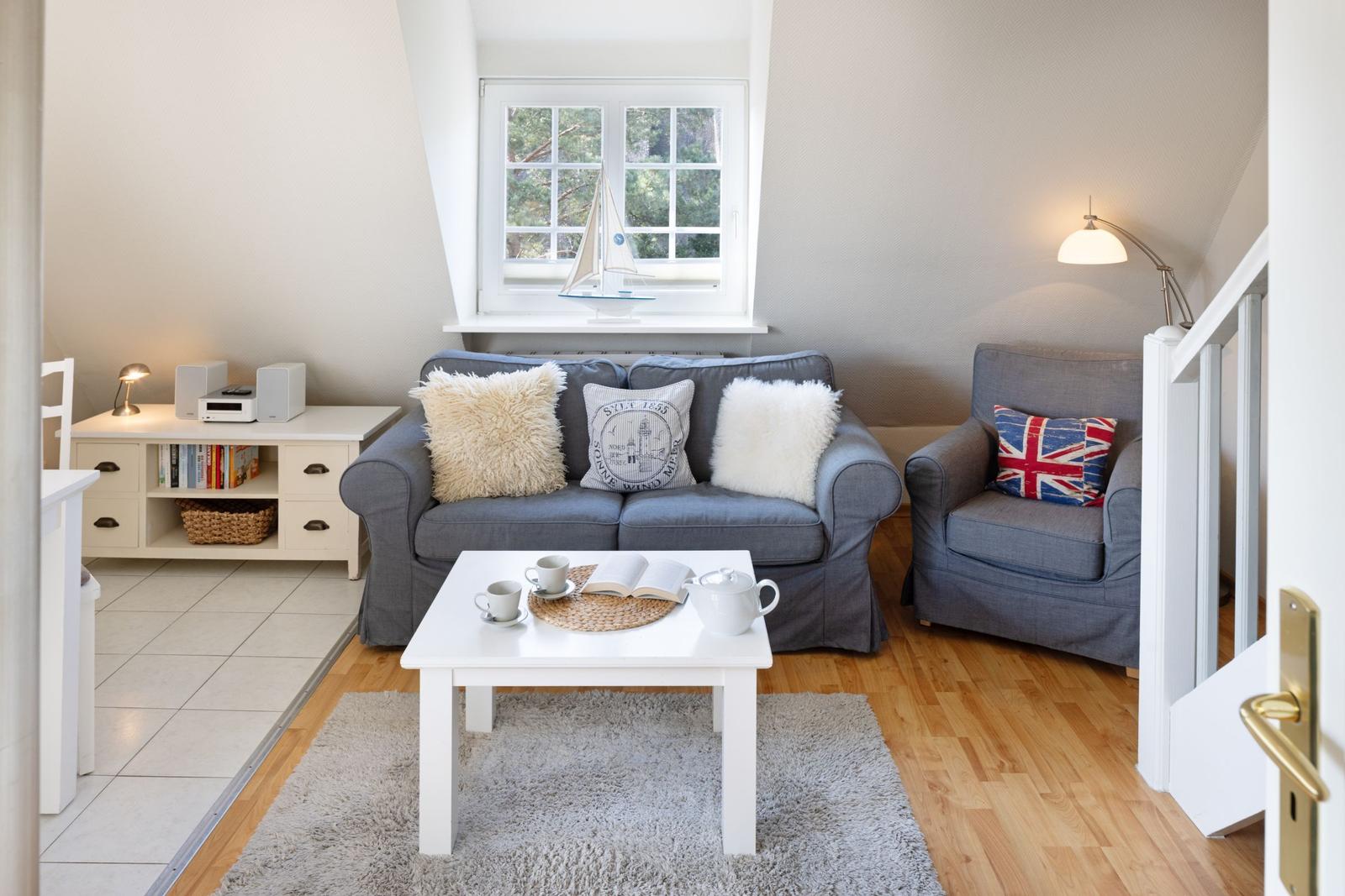 Ein Wohnzimmer mit grauem Sofa, weißen Kissen und einem weißen Couchtisch.
