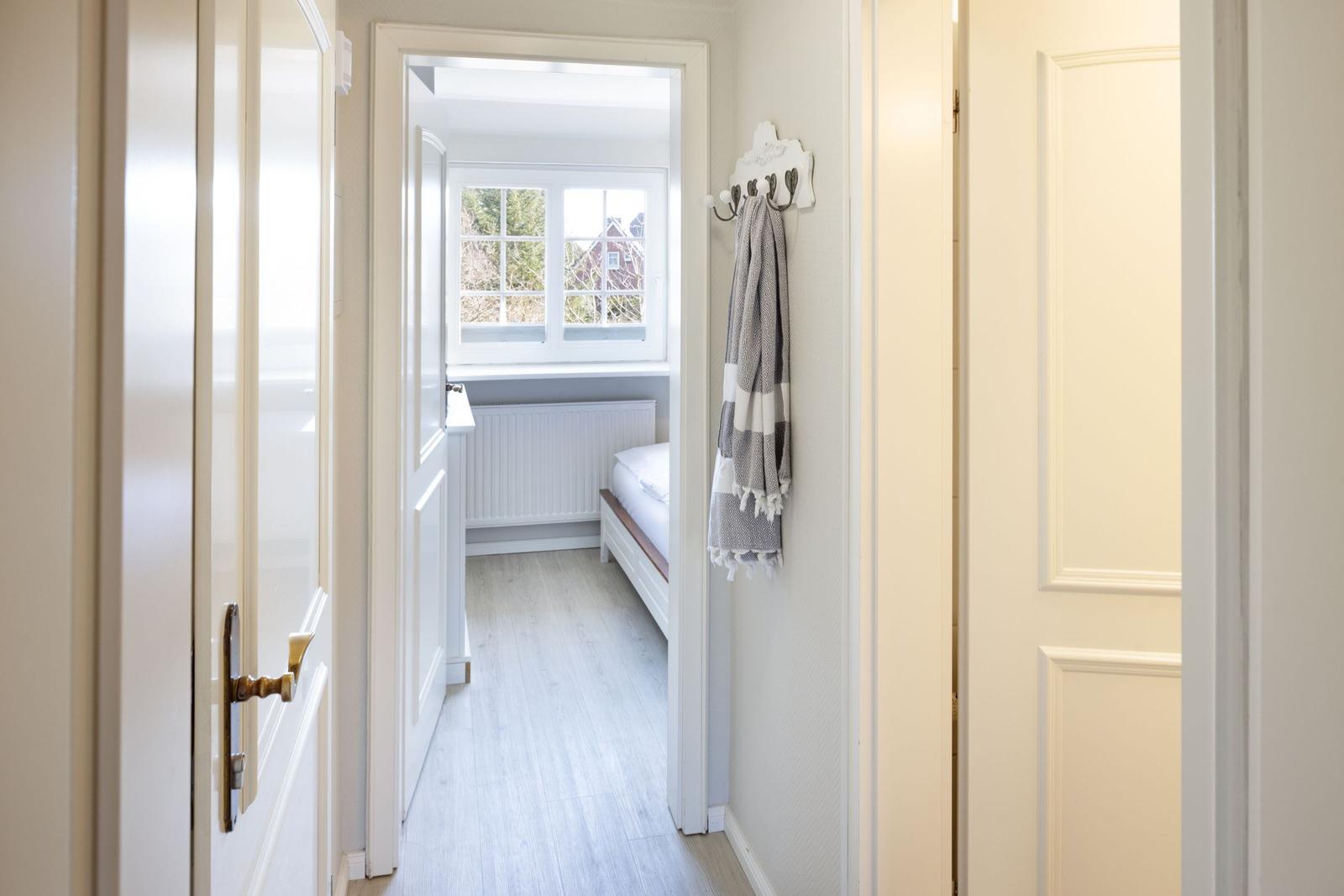 Schlafzimmer mit Fenster, Bett und Handtuchhalter an der Wand.