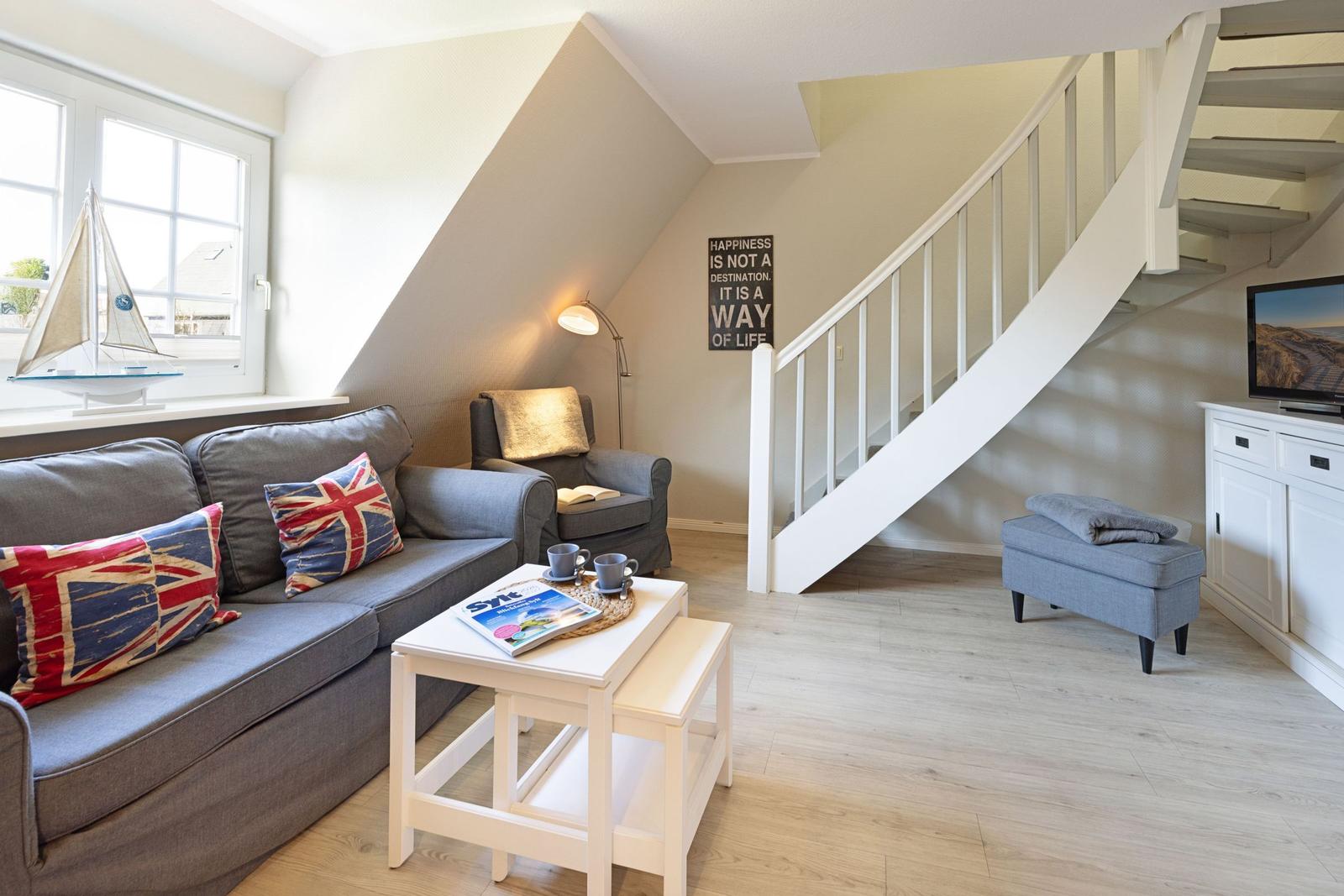 Wohnzimmer mit Sofa, Treppenhaus und Fernseher