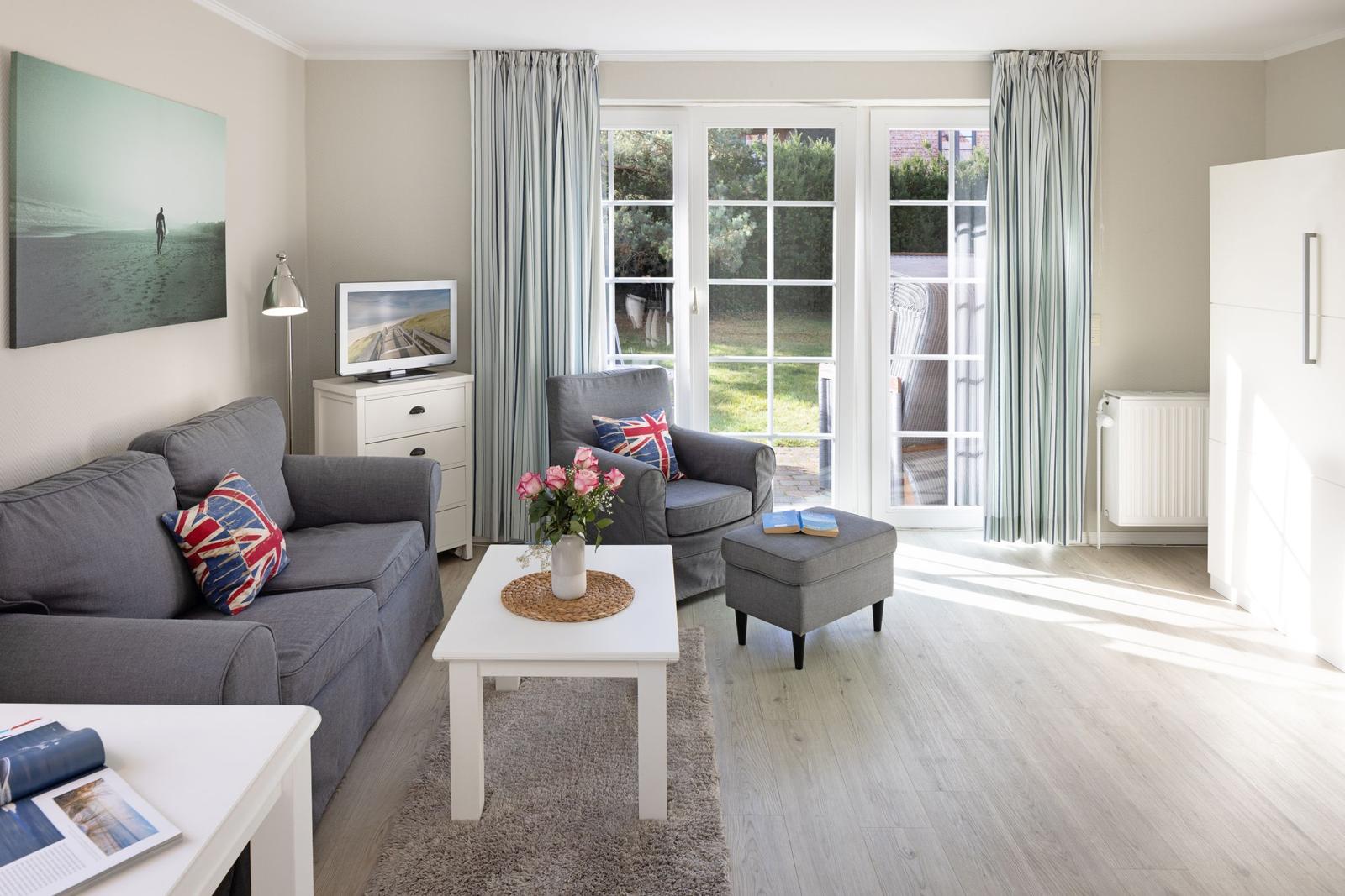 Living room with gray sofa, white furniture, and garden view.