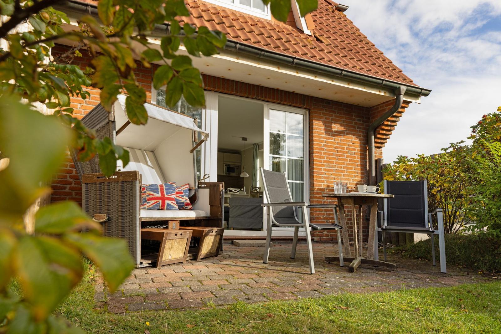 Terrace with seating and view into the house. Garden area with plants and stone paving.