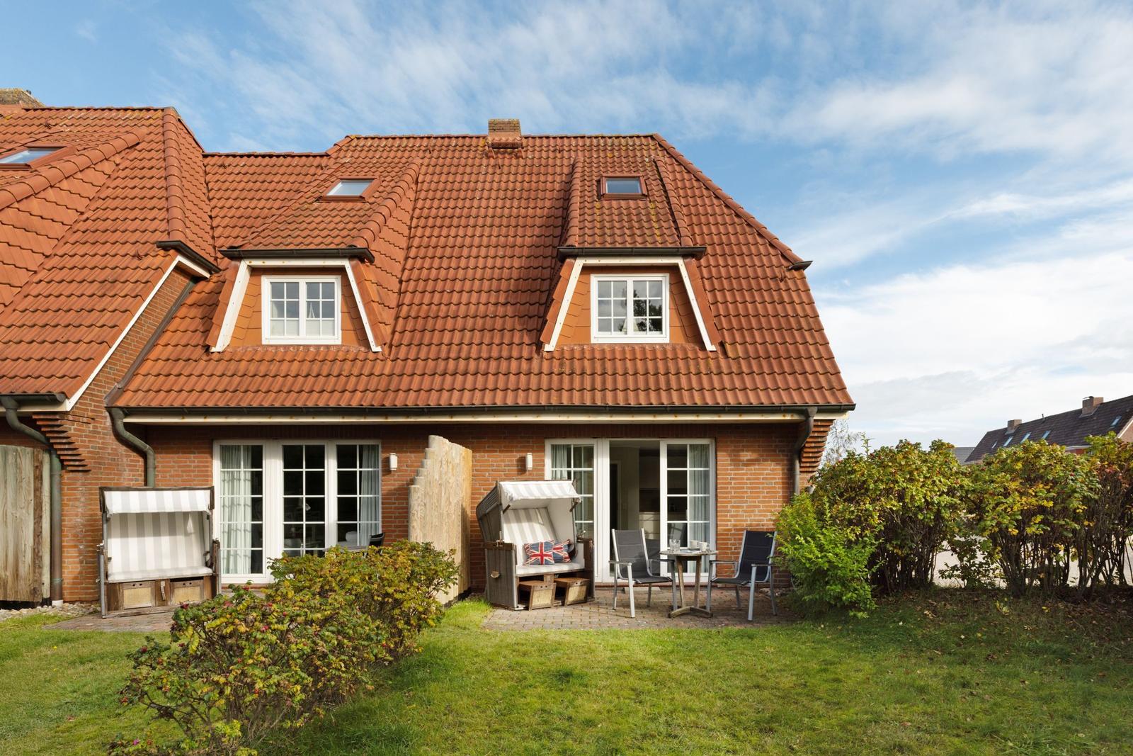 House with red roof, terrace, and garden. Windows and doors are white.