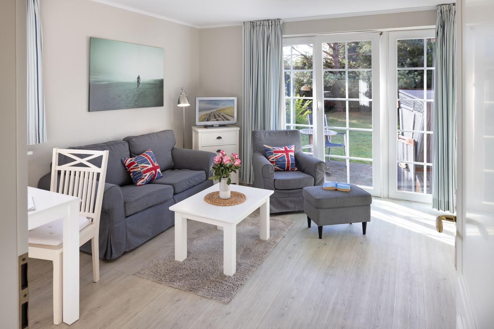 Living room with sofa, armchair, and table. Door leads to the terrace.