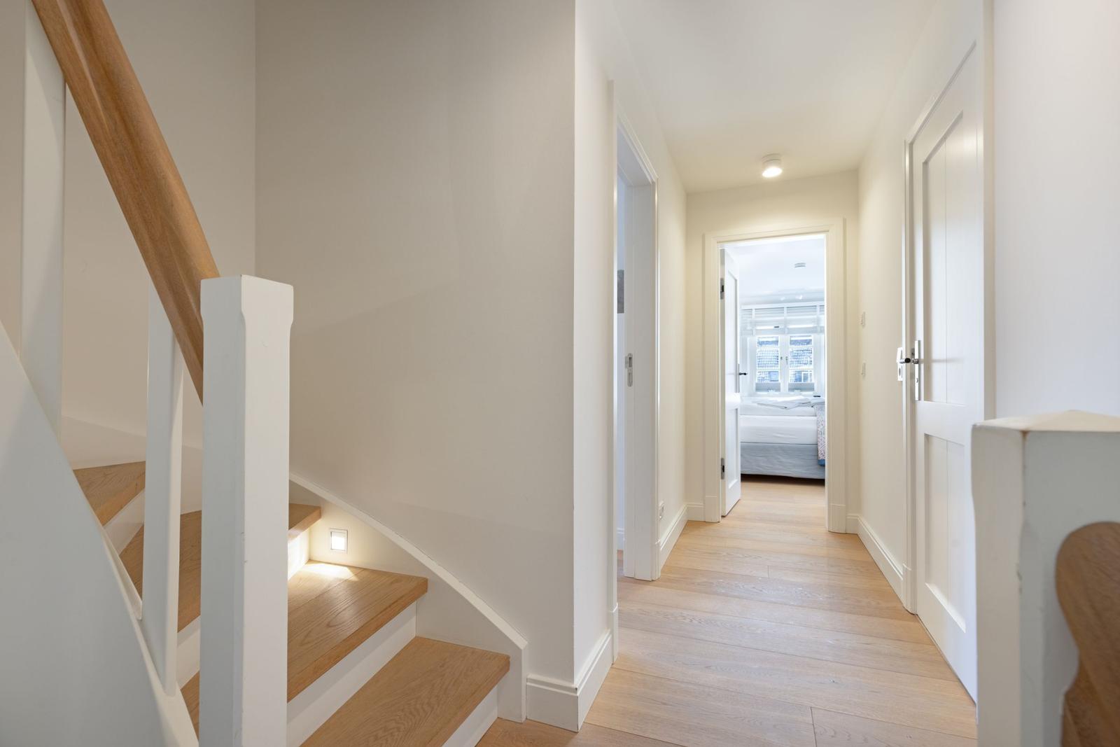 Hausflur mit Holztreppe und Tür zu Schlafzimmer