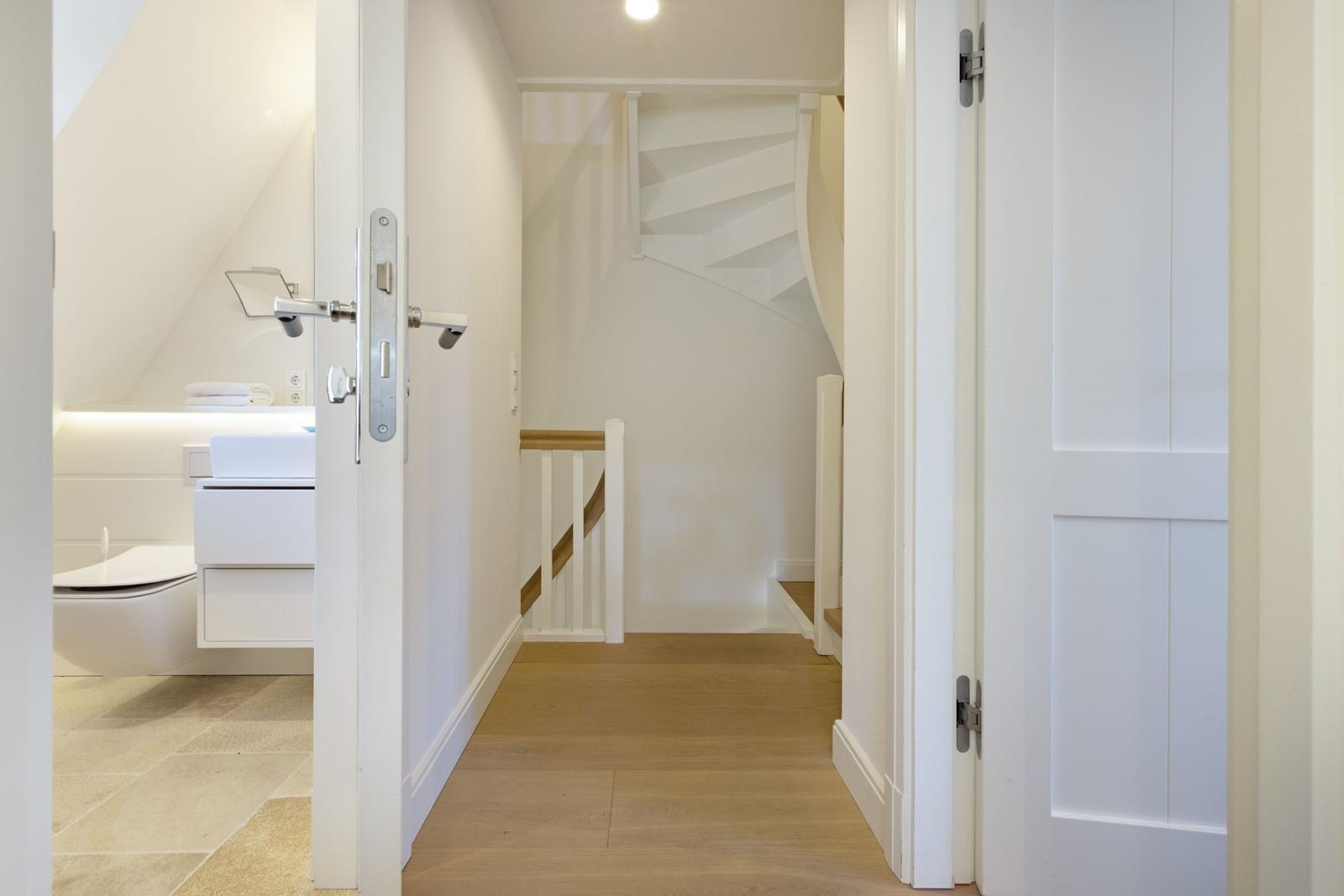 Hinterer Flur mit Treppe und Blick in die moderne Toilette.