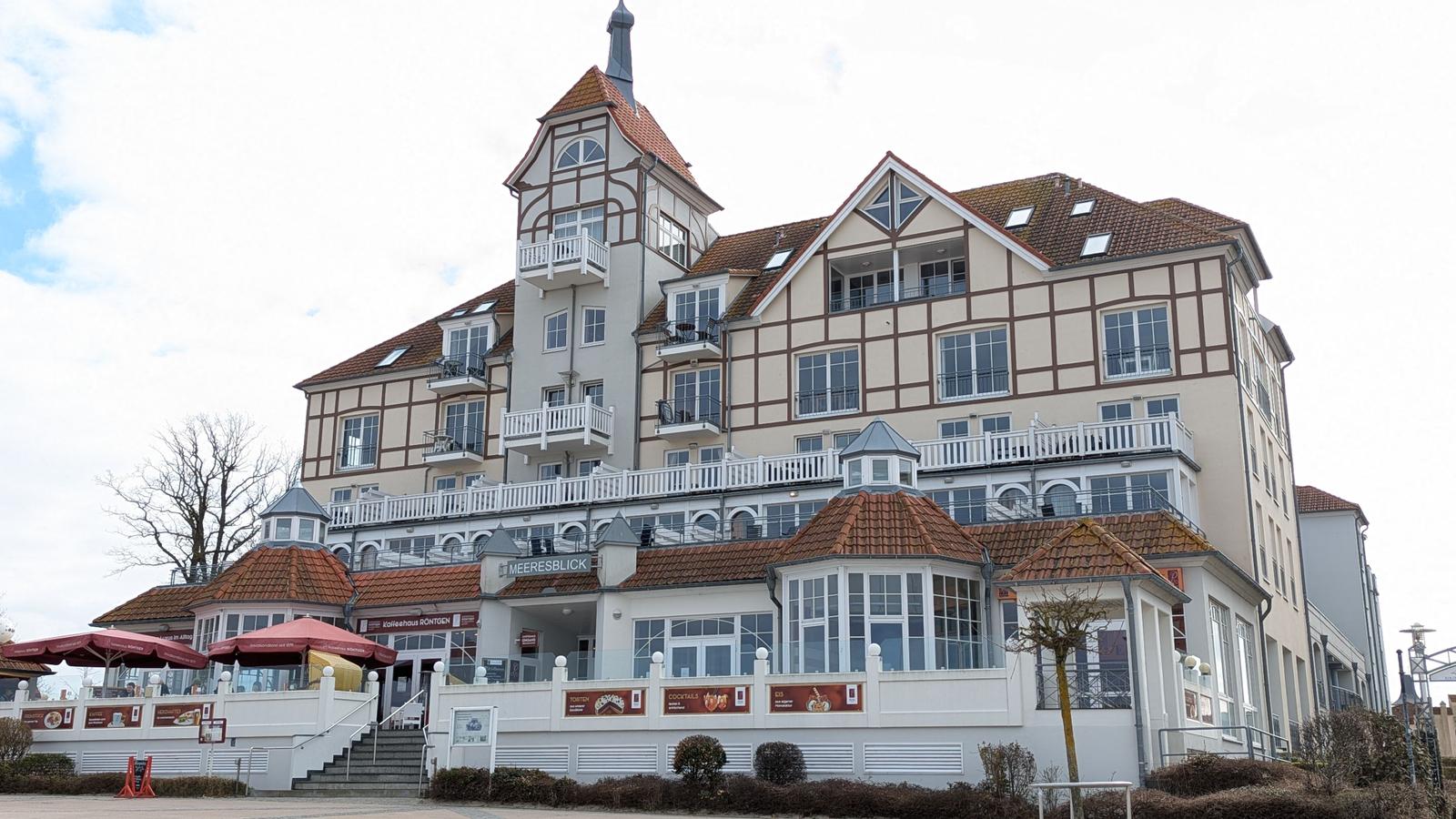 Meeresblick-Hotel mit Terrasse, Balkonen und rotem Ziegeldach.