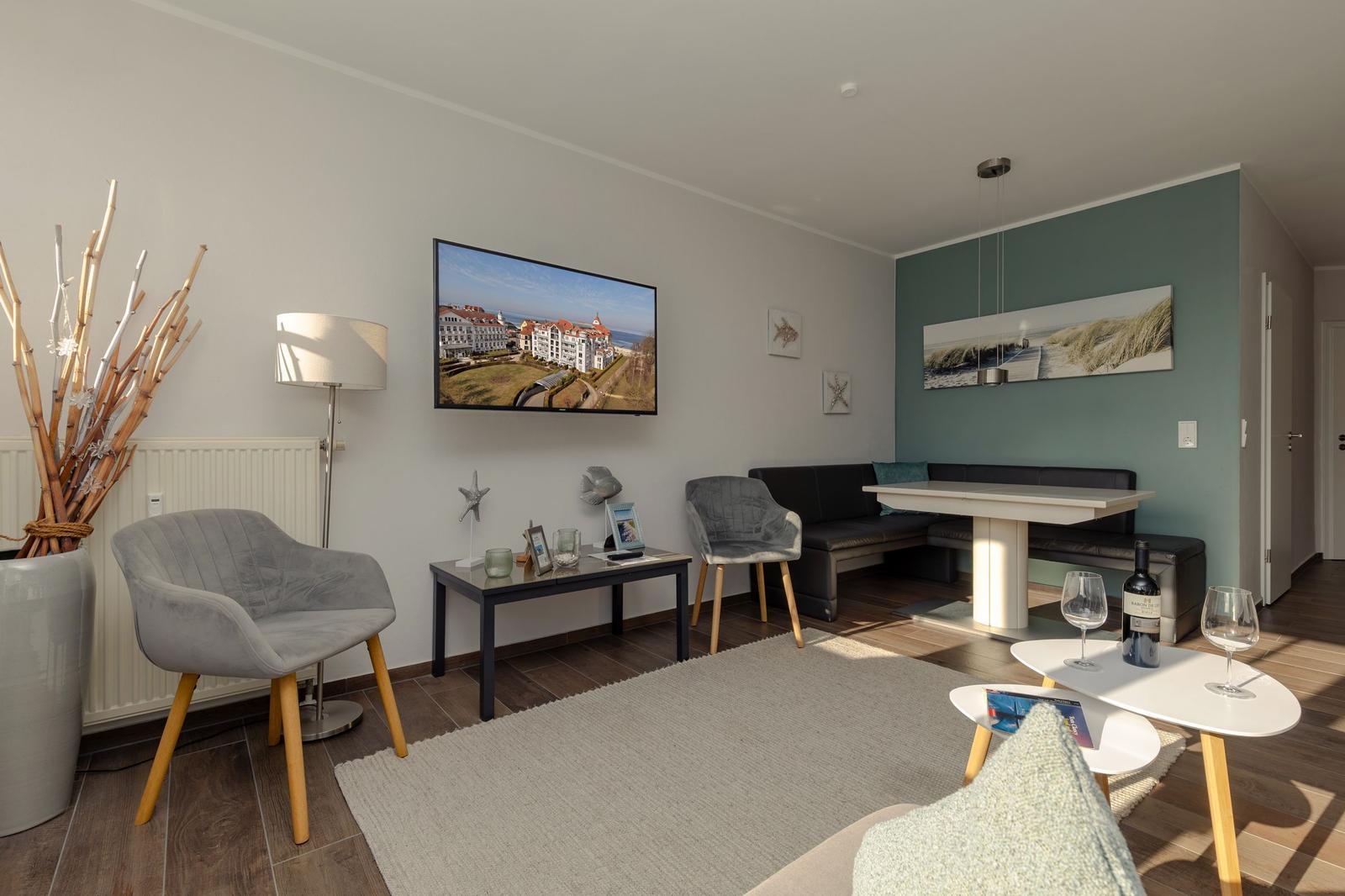 Wohnzimmer mit Sofa, Tisch und Fernseher an der Wand.