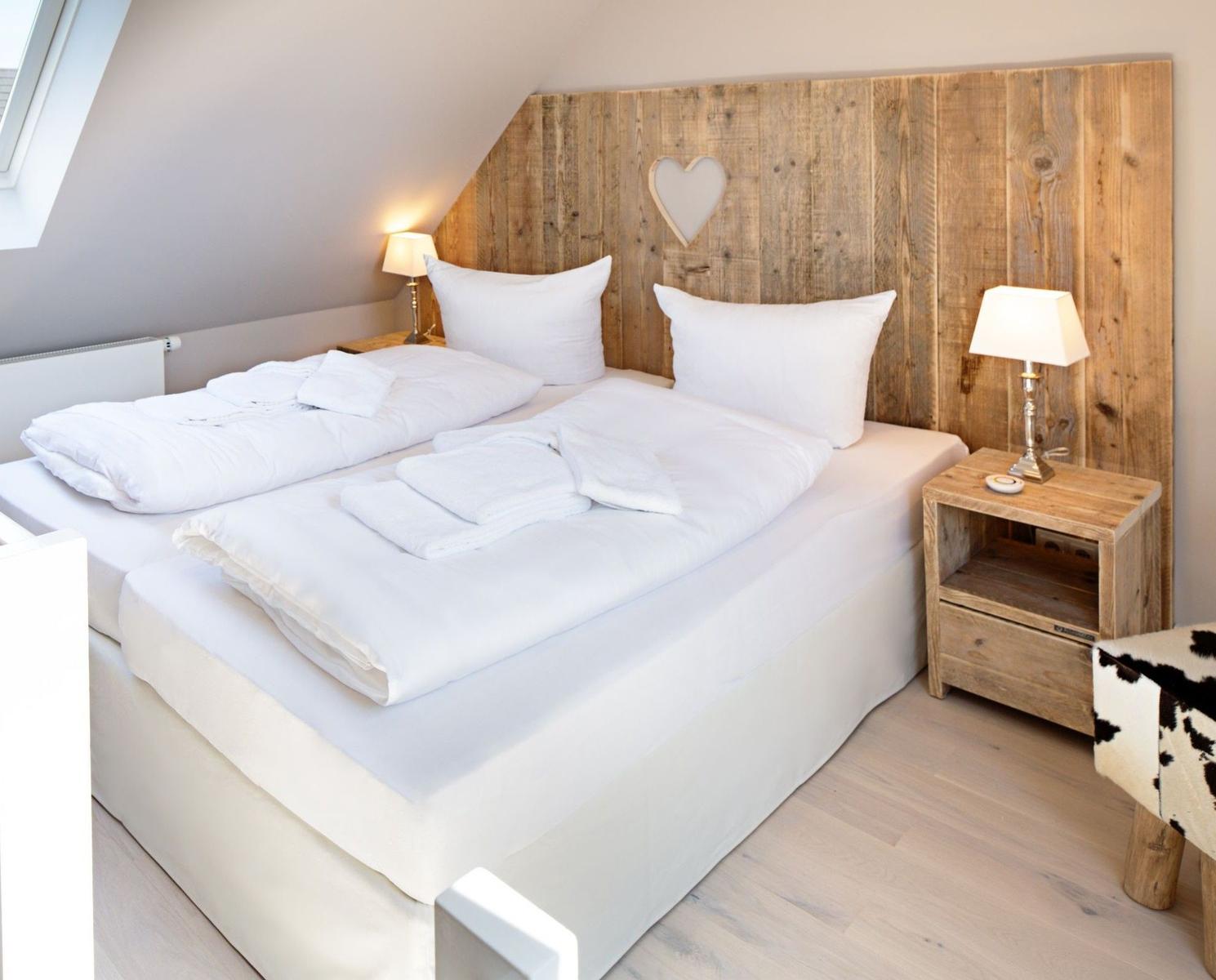 Schlafzimmer mit Doppelbett, Holzpaneelen und Nachttischen.