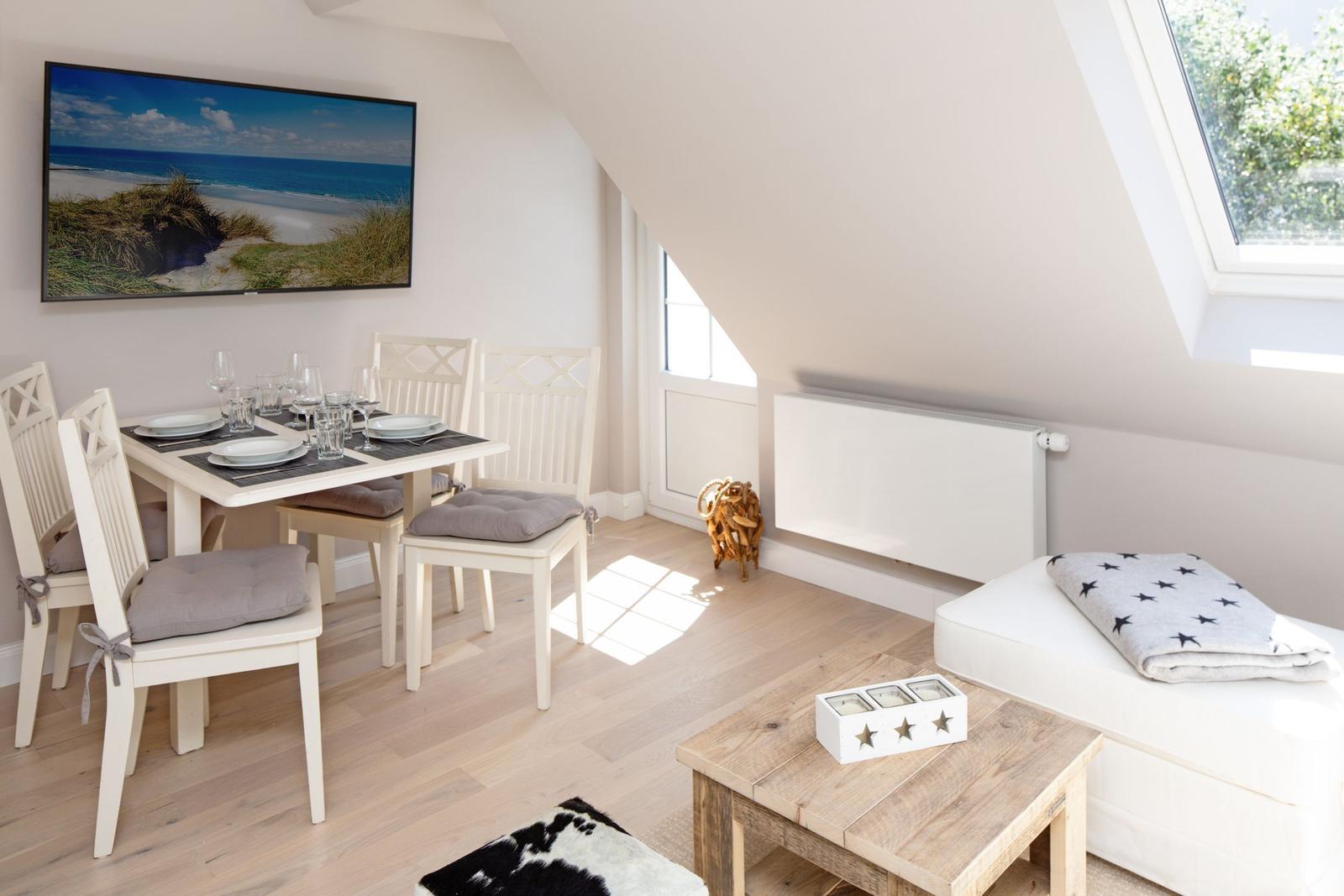 Essbereich mit Tisch, Stühlen und Fernseher unter Dachschrägen