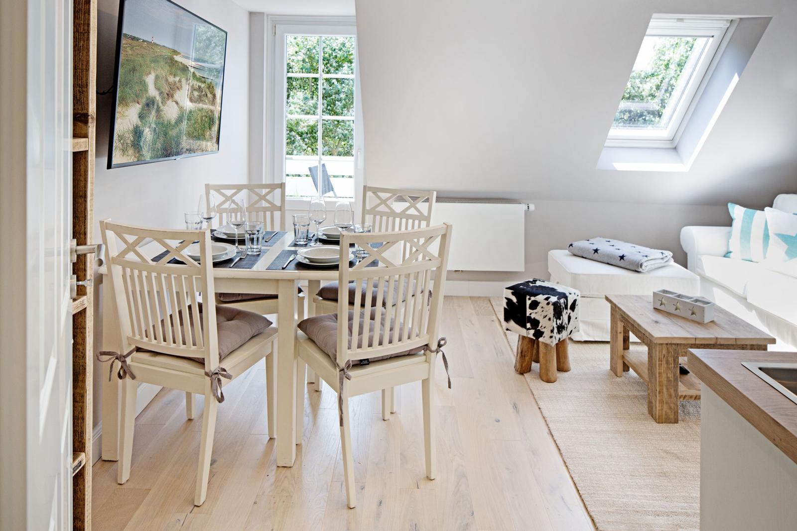 Essbereich mit Tisch und Stühlen, Wohnbereich mit Sofa und Dachfenster.
