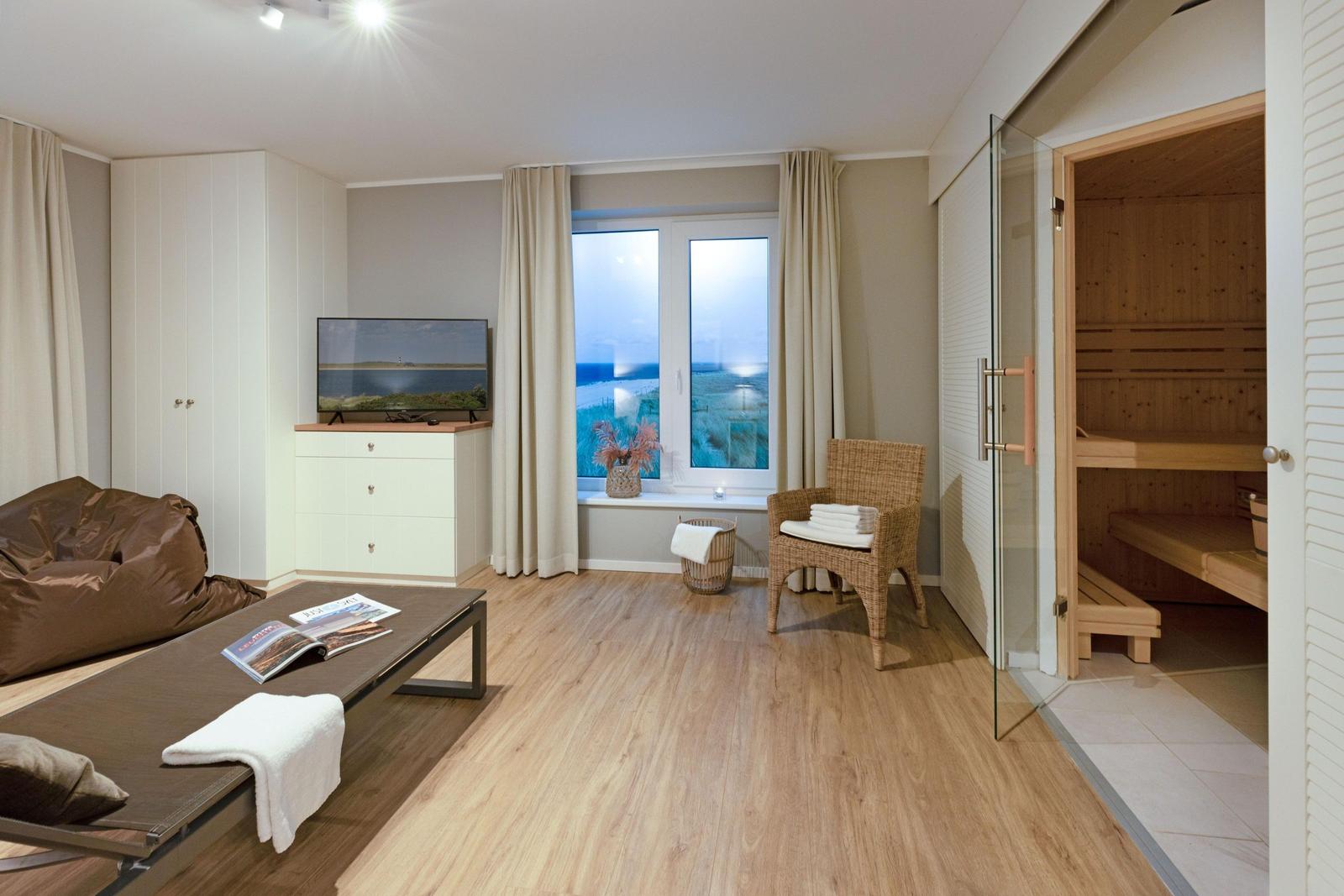 Wohnraum mit Sauna, TV, Fensterblick und Sitzgelegenheiten.