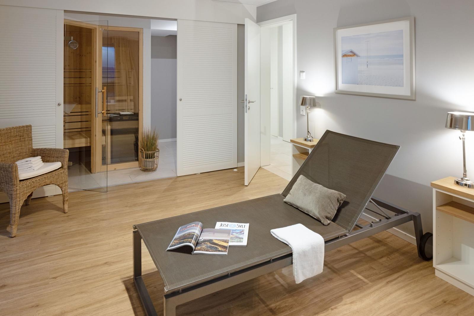 Ein Raum mit Liege, Badewanne und Sauna. Holzfußboden und moderne Einrichtung.