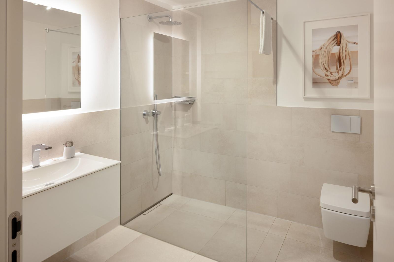 Moderne Badezimmer mit Dusche, Waschbecken und Toilette. Wandbild und Badewanne sind sichtbar.