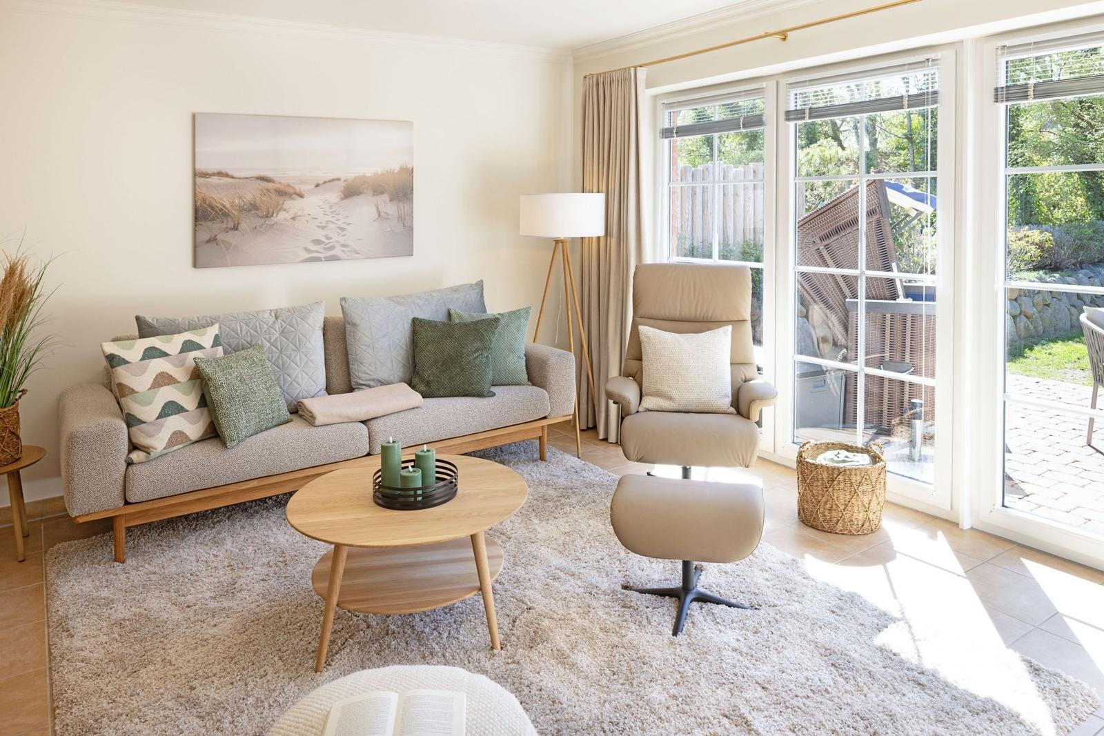 Wohnzimmer mit Sofa, Sessel und Glasfront zur Terrasse.
