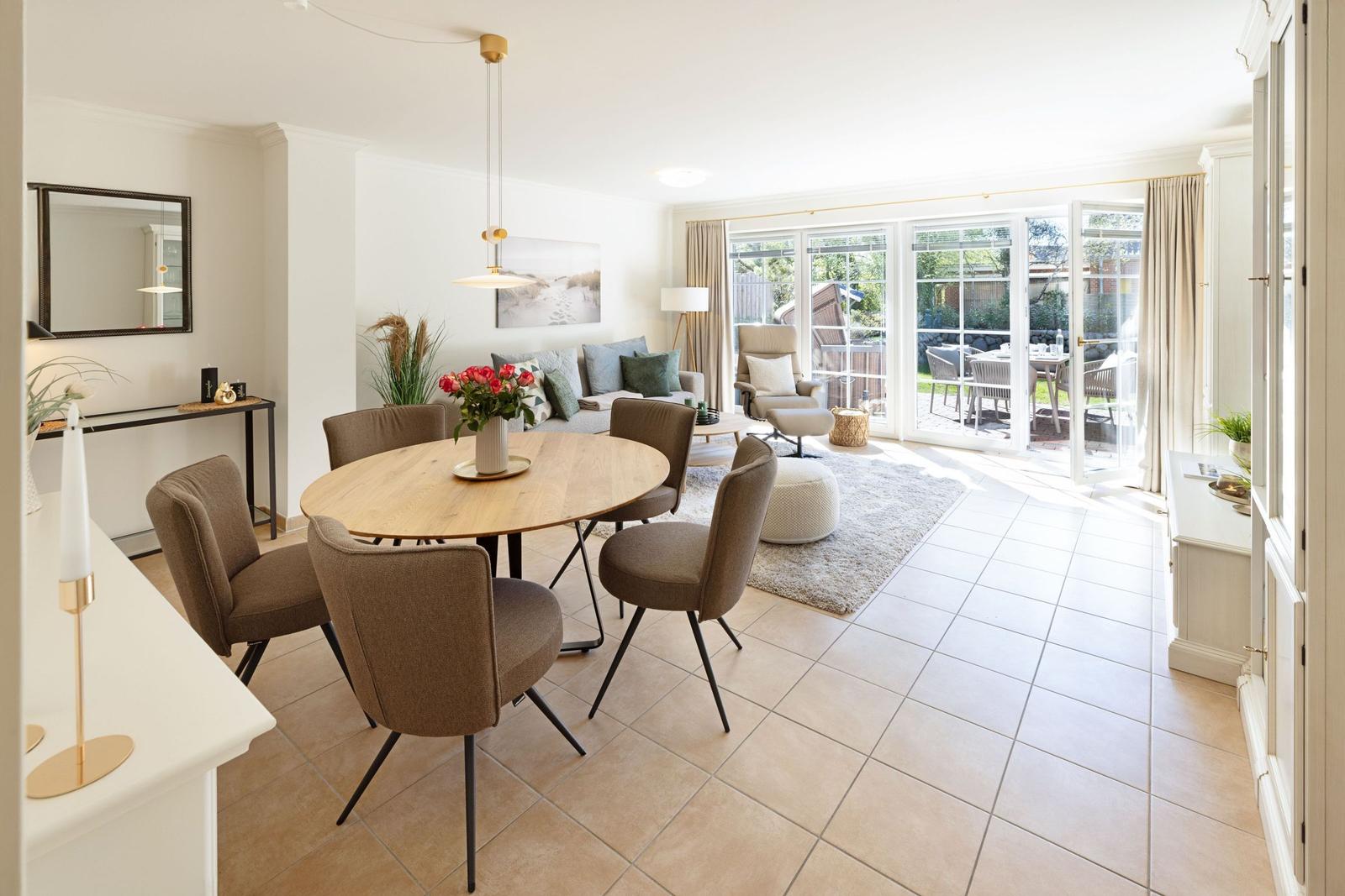Essbereich mit runden Tisch und Stühlen, Wohnbereich mit Sofa und Blick auf Terrasse.