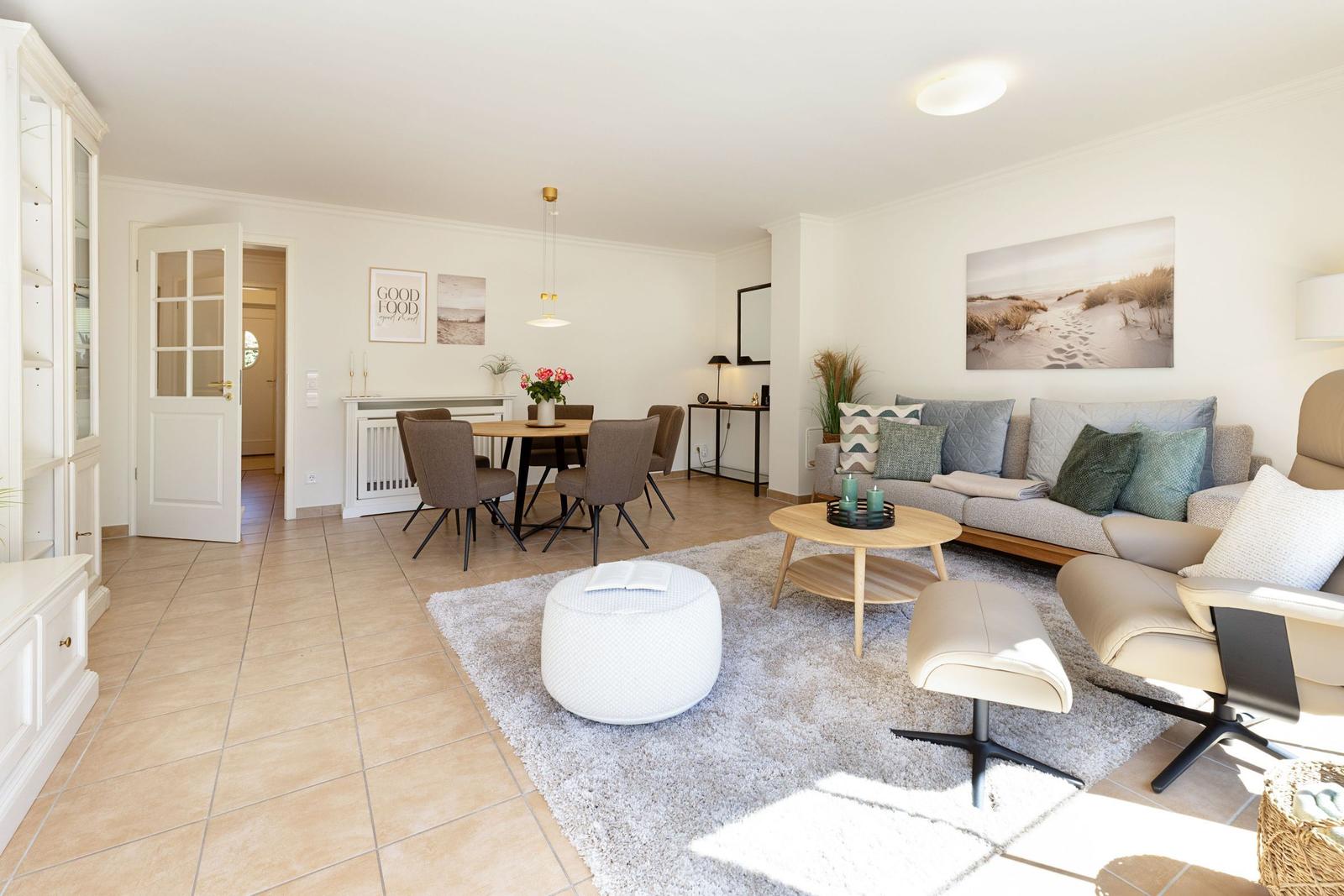 Wohn- und Essbereich mit Sofa, Tisch und Stühlen. Wandbild und Teppich sichtbar.