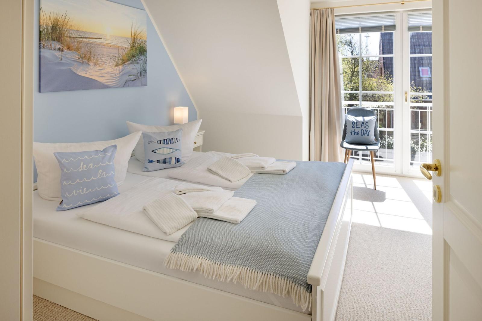 Schlafzimmer mit Bett, Kissen und Blick auf Balkon.
