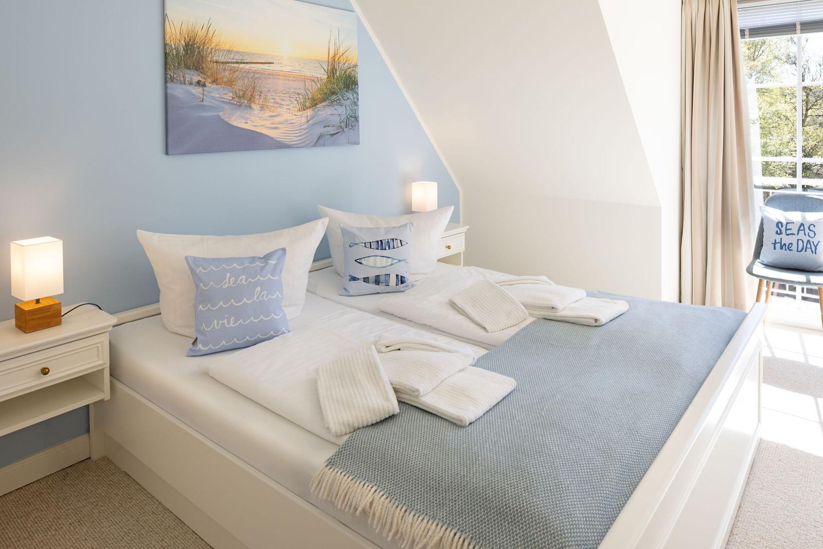 Schlafzimmer mit Doppelbett, blauer Wand und Fenster mit Blick.